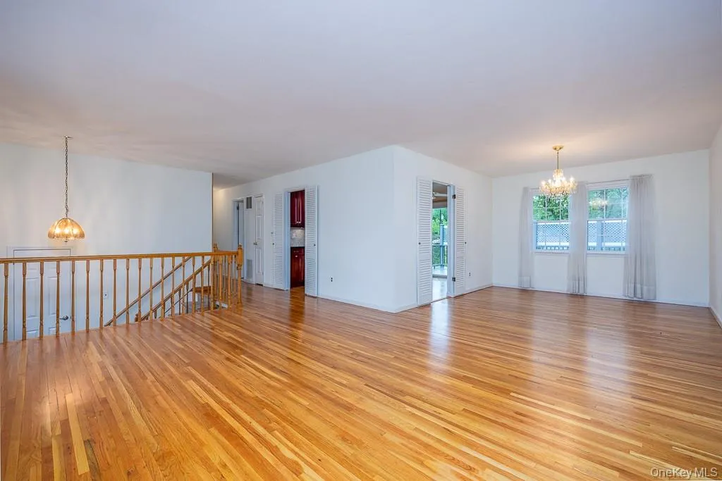 Empty room featuring a chandelier, light wood-style floors, and baseboards Empty room featuring a chandelier, light wood-style floors, and baseboards