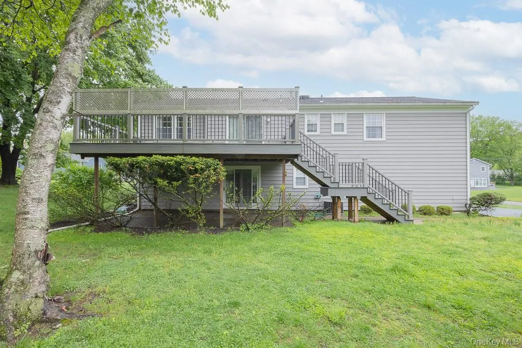 Rear view of property with stairway, a wooden deck, and a lawn Rear view of property with stairway, a wooden deck, and a lawn