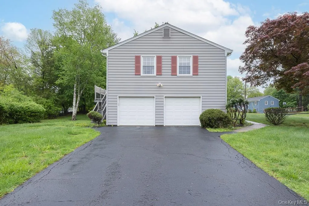 View of property exterior featuring asphalt driveway, a lawn, and a garage View of property exterior featuring asphalt driveway, a lawn, and a garage
