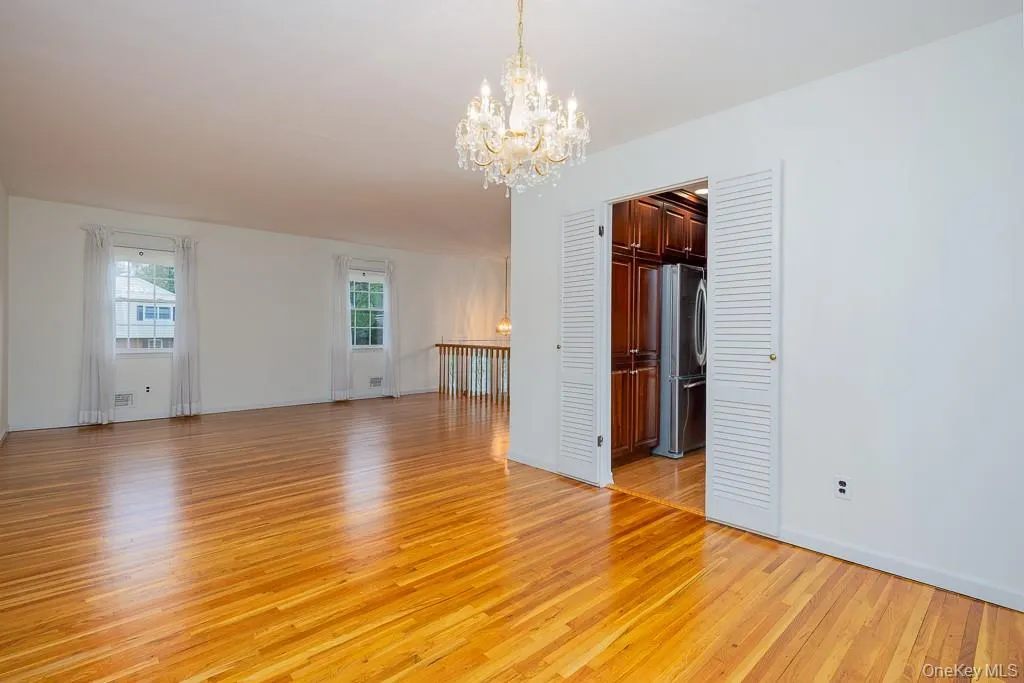 Empty room featuring light wood finished floors, a chandelier, and baseboards Empty room featuring light wood finished floors, a chandelier, and baseboards
