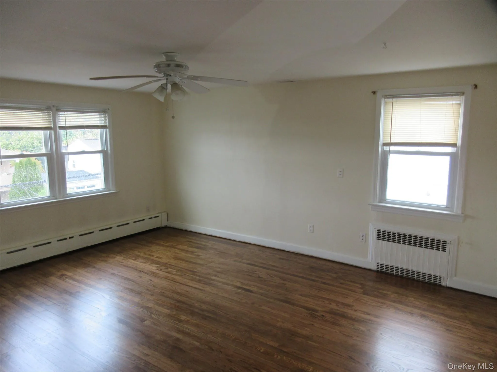 Spare room with dark wood-style flooring, radiator, baseboard heating, and ceiling fan Spare room with dark wood-style flooring, radiator, baseboard heating, and ceiling fan