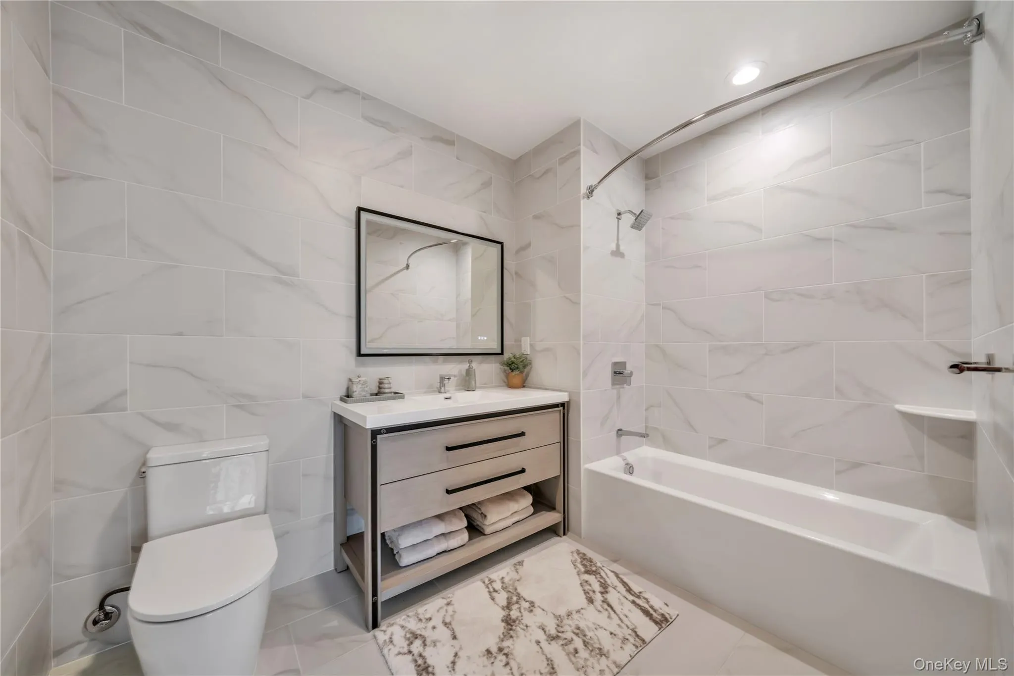 Bathroom featuring tile walls, vanity, toilet, and shower / washtub combination Bathroom featuring tile walls, vanity, toilet, and shower / washtub combination
