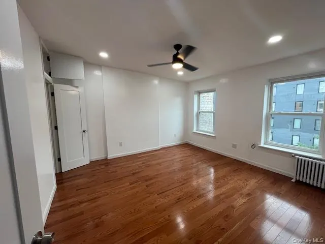 Unfurnished bedroom featuring wood finished floors, radiator heating unit, ceiling fan, and recessed lighting Unfurnished bedroom featuring wood finished floors, radiator heating unit, ceiling fan, and recessed lighting