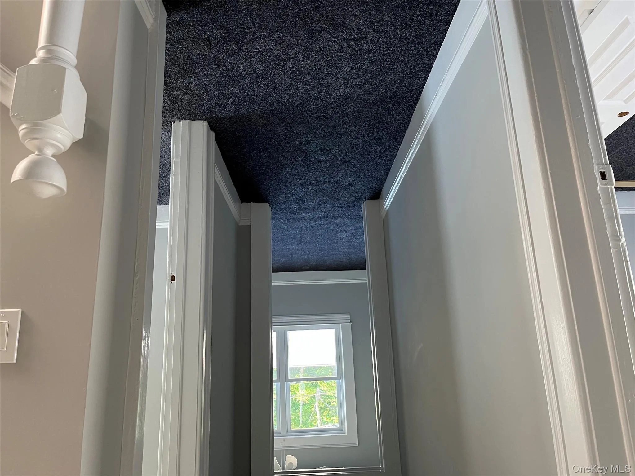Corridor featuring dark colored carpet and baseboards Corridor featuring dark colored carpet and baseboards
