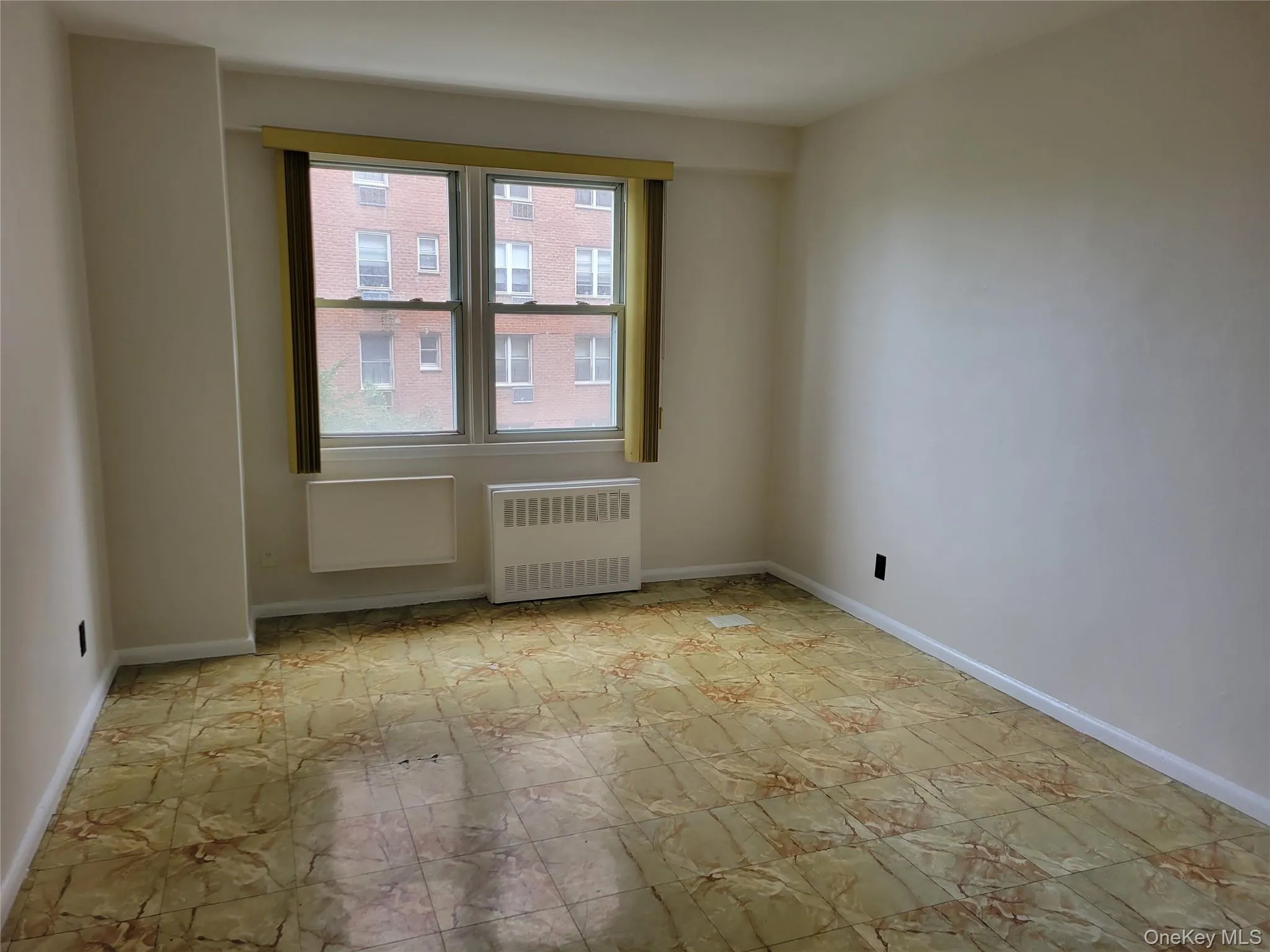 Empty room featuring radiator heating unit and baseboards Empty room featuring radiator heating unit and baseboards