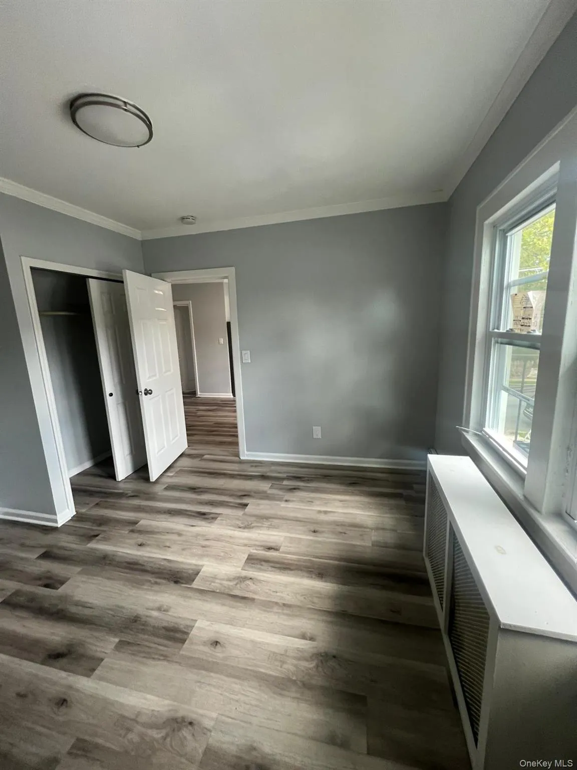 Unfurnished bedroom with wood finished floors, crown molding, and a closet Unfurnished bedroom with wood finished floors, crown molding, and a closet