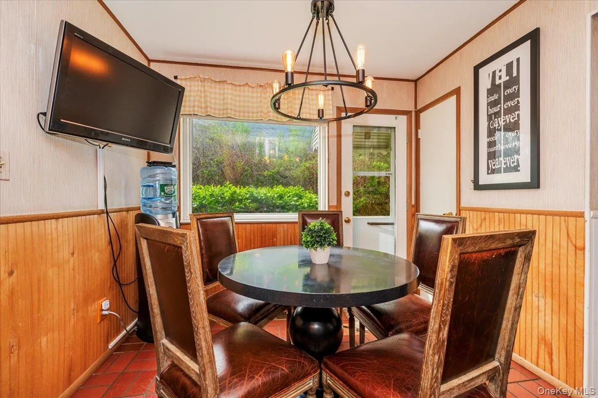 Dining room with wooden walls, a chandelier, wainscoting, crown molding, and dark tile patterned floors Dining room with wooden walls, a chandelier, wainscoting, crown molding, and dark tile patterned floors