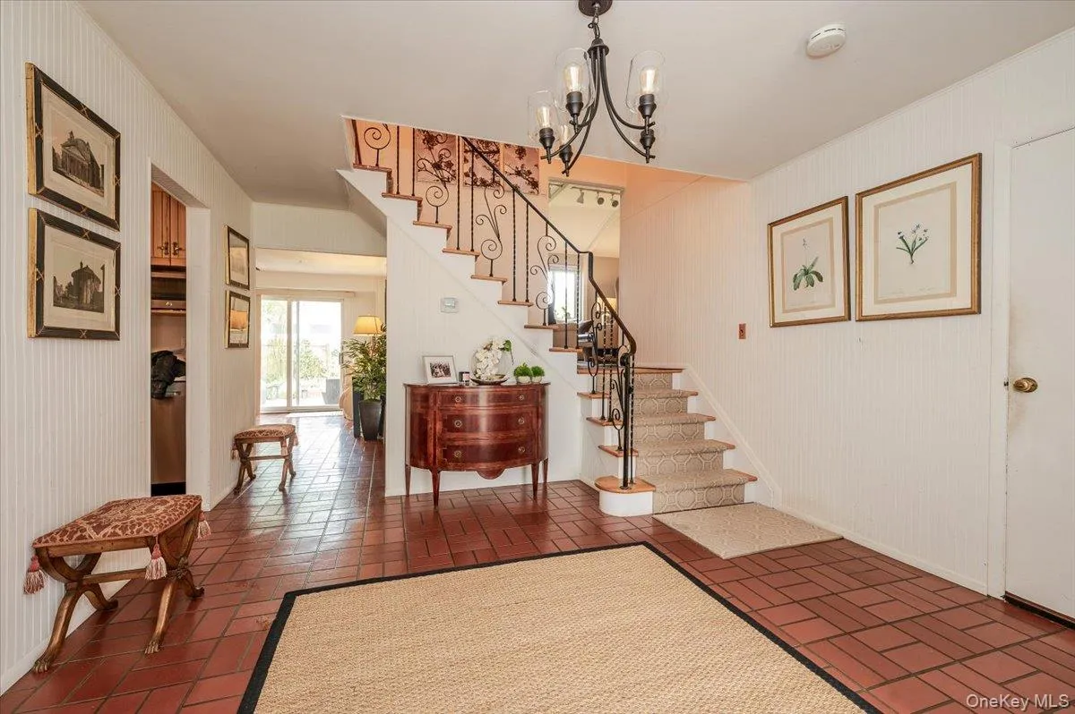 Foyer entrance featuring stairway, brick patterned flooring, and a chandelier Foyer entrance featuring stairway, brick patterned flooring, and a chandelier