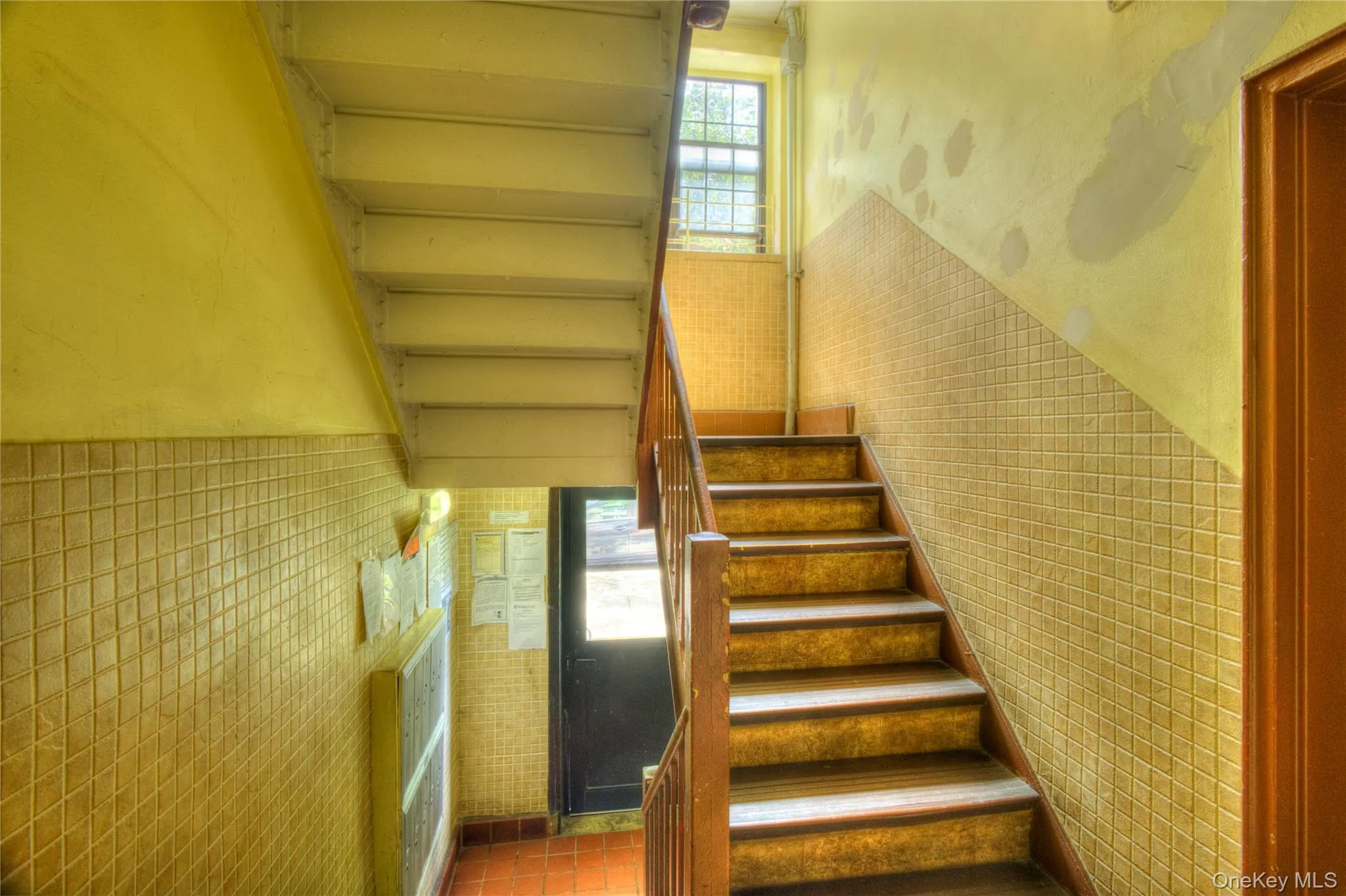 Stairway featuring plenty of natural light, tile walls, and tile patterned flooring Stairway featuring plenty of natural light, tile walls, and tile patterned flooring
