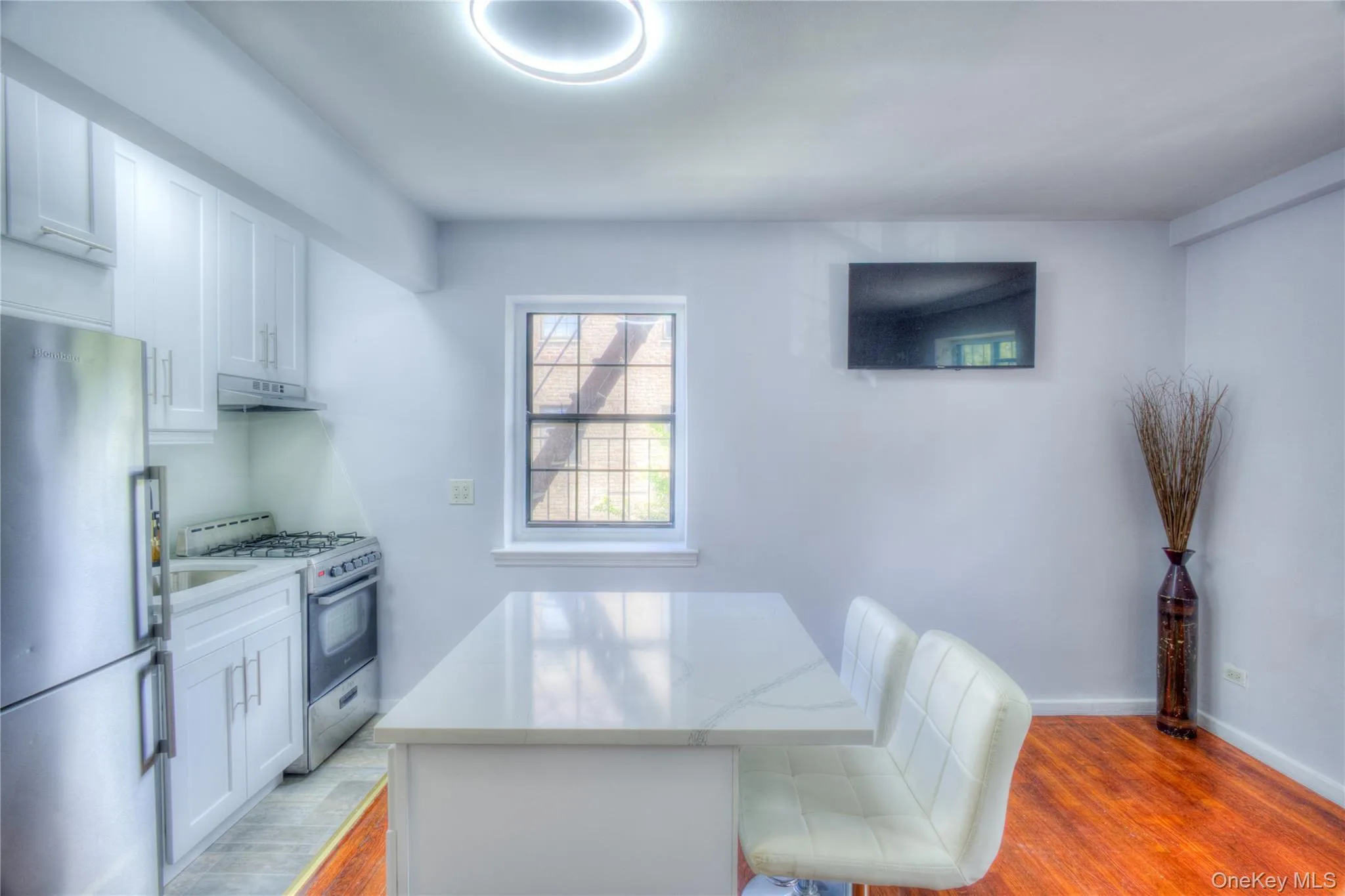 Kitchen with light wood-style floors, freestanding refrigerator, stainless steel gas range oven, and white cabinetry Kitchen with light wood-style floors, freestanding refrigerator, stainless steel gas range oven, and white cabinetry