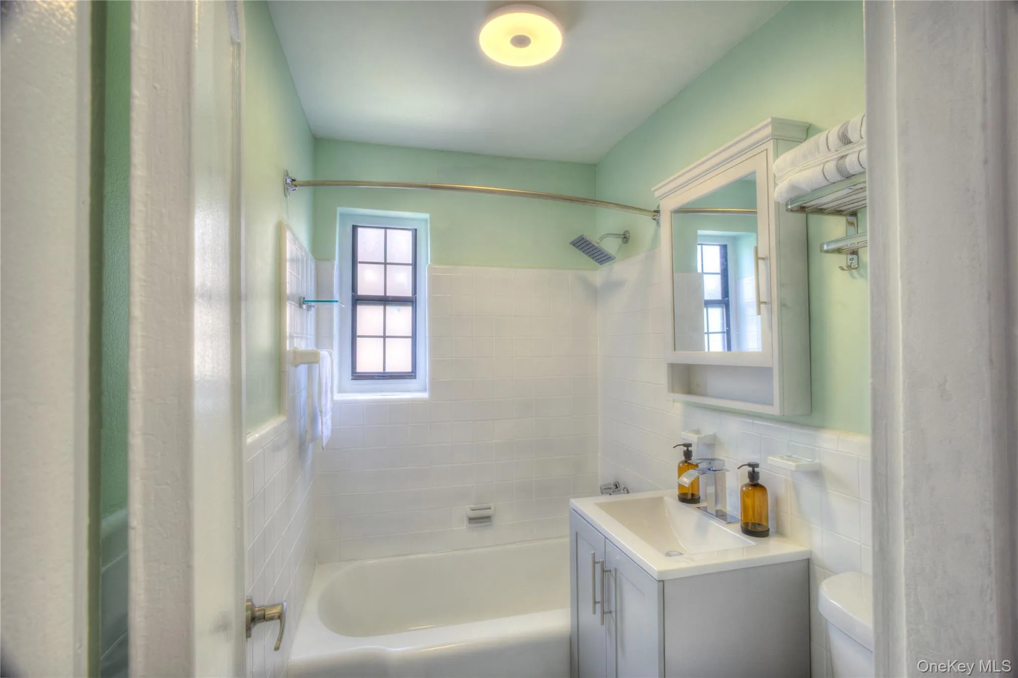 Bathroom featuring shower / tub combination, vanity, tile walls, and tasteful backsplash Bathroom featuring shower / tub combination, vanity, tile walls, and tasteful backsplash