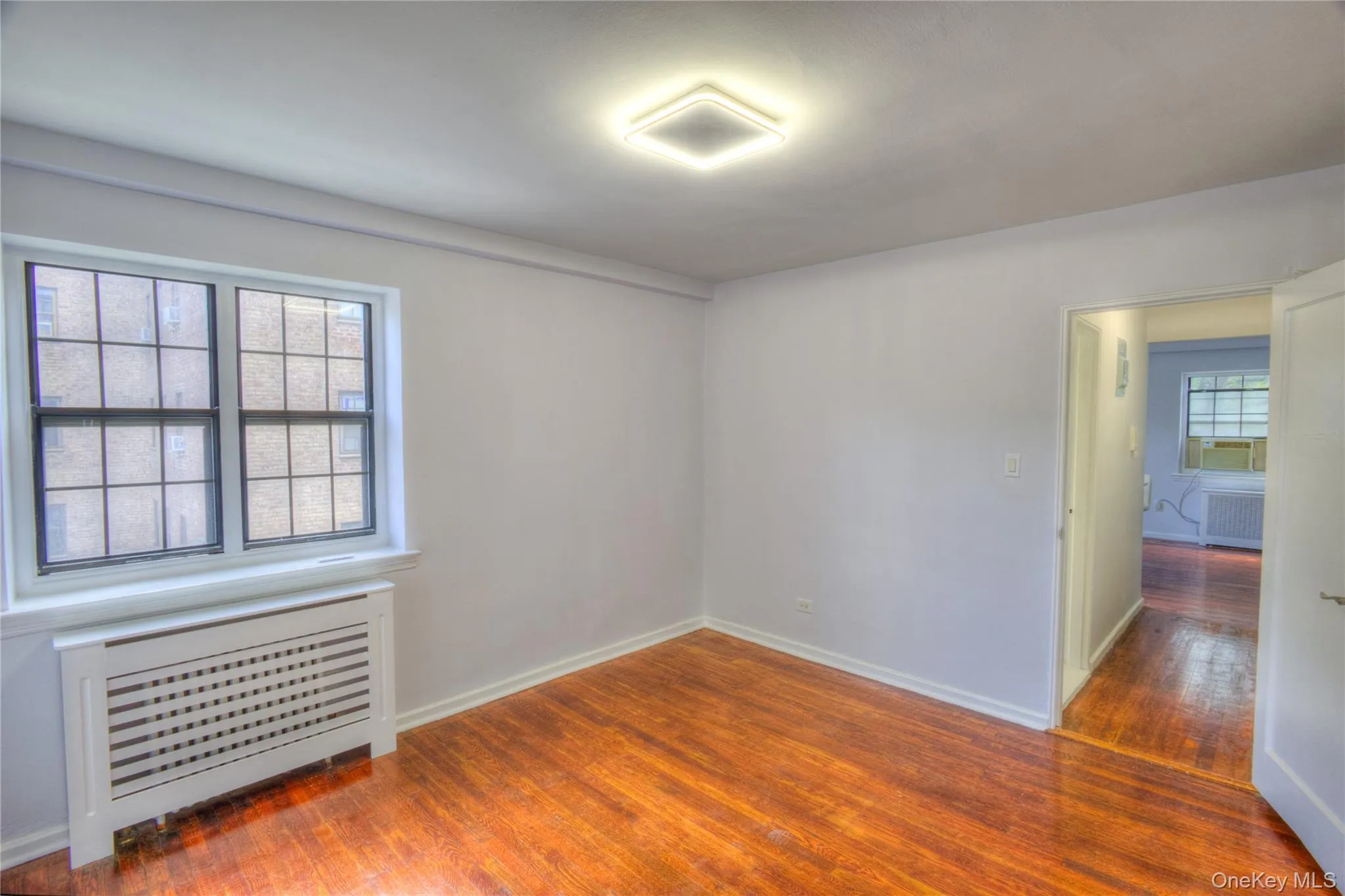 Unfurnished room with radiator heating unit and dark wood-style floors Unfurnished room with radiator heating unit and dark wood-style floors