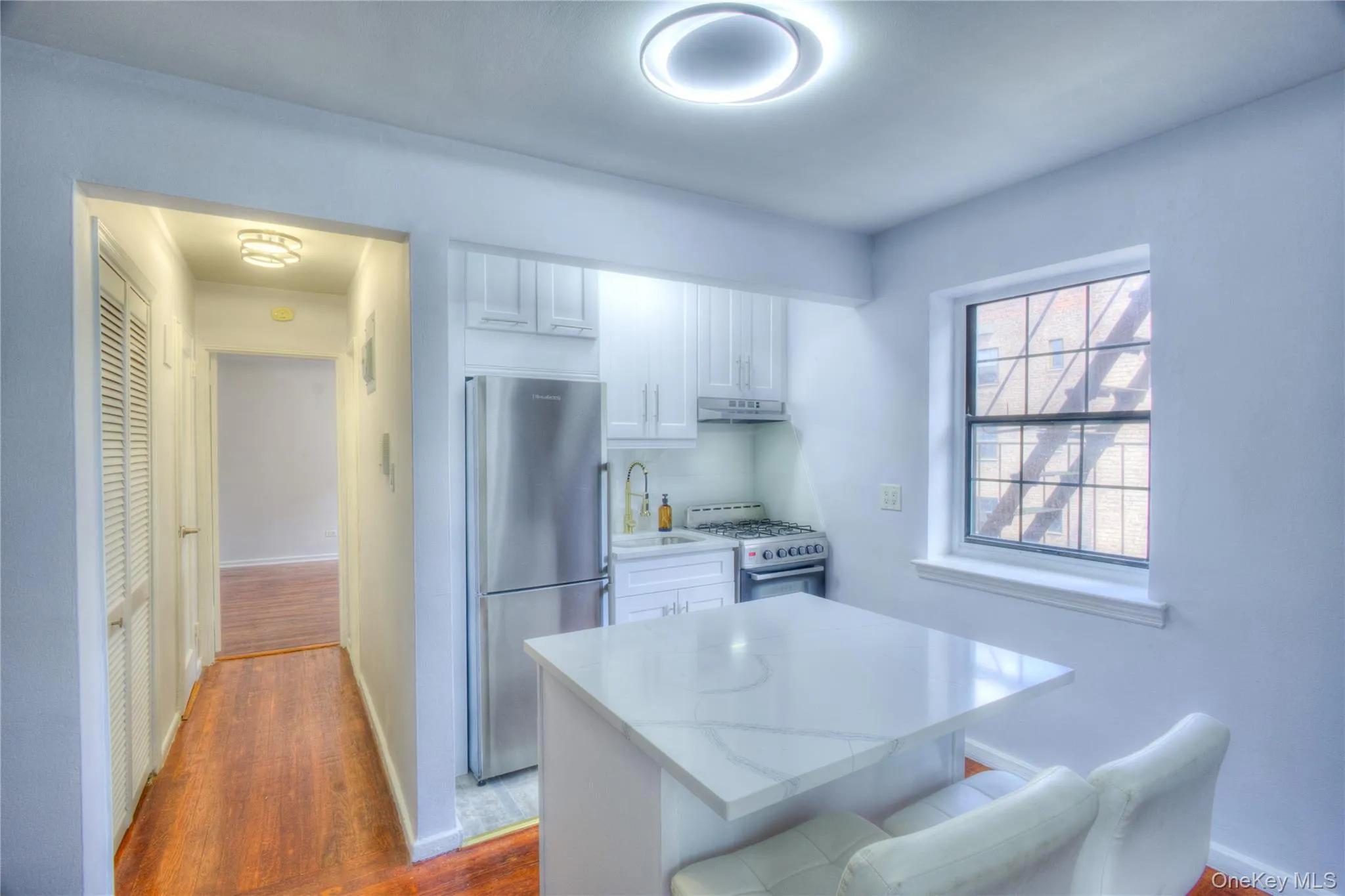 Kitchen featuring white cabinets, dark wood-style floors, freestanding refrigerator, a breakfast bar area, and white gas range Kitchen featuring white cabinets, dark wood-style floors, freestanding refrigerator, a breakfast bar area, and white gas range