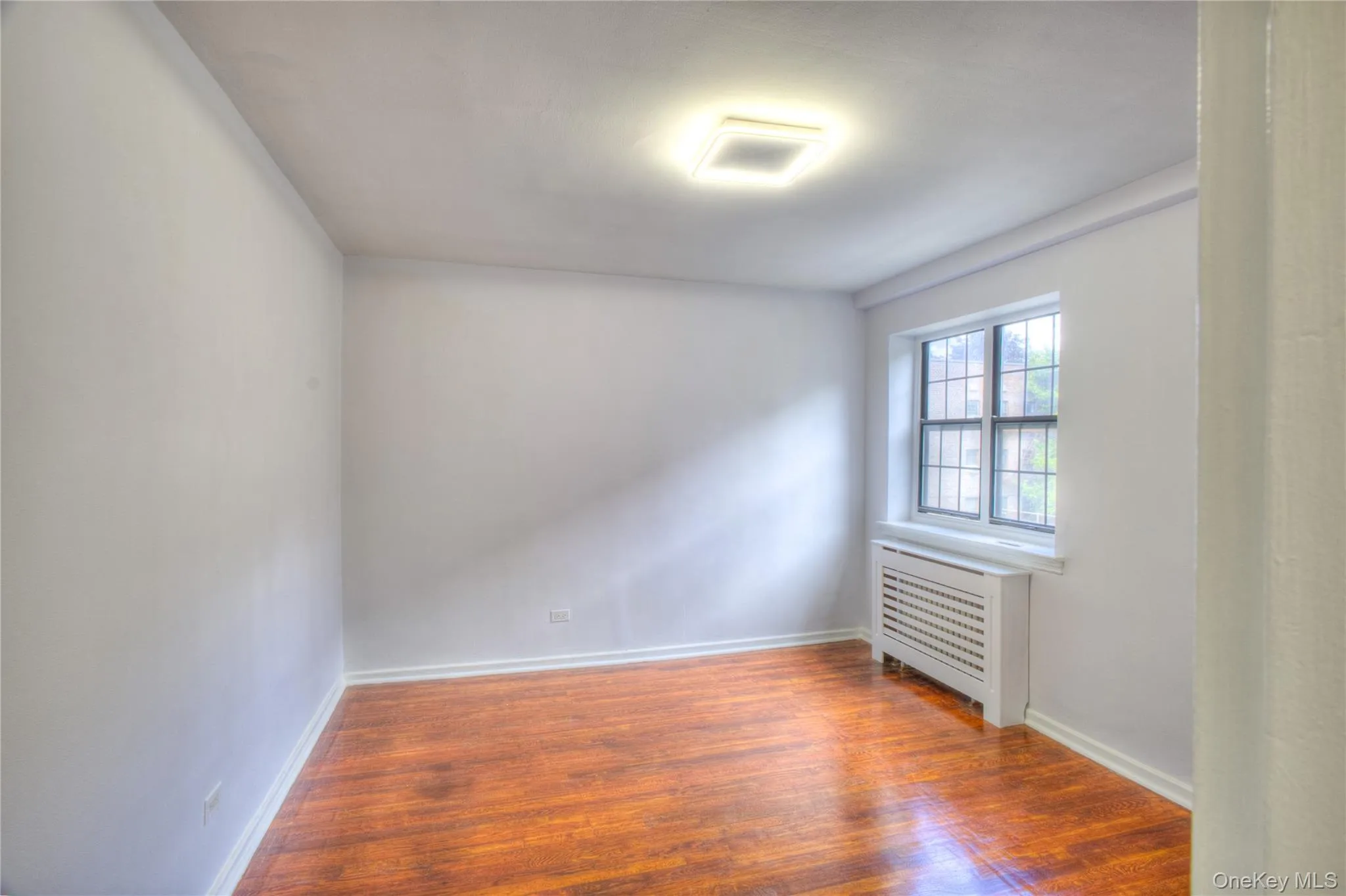 Empty room with radiator heating unit and wood finished floors Empty room with radiator heating unit and wood finished floors