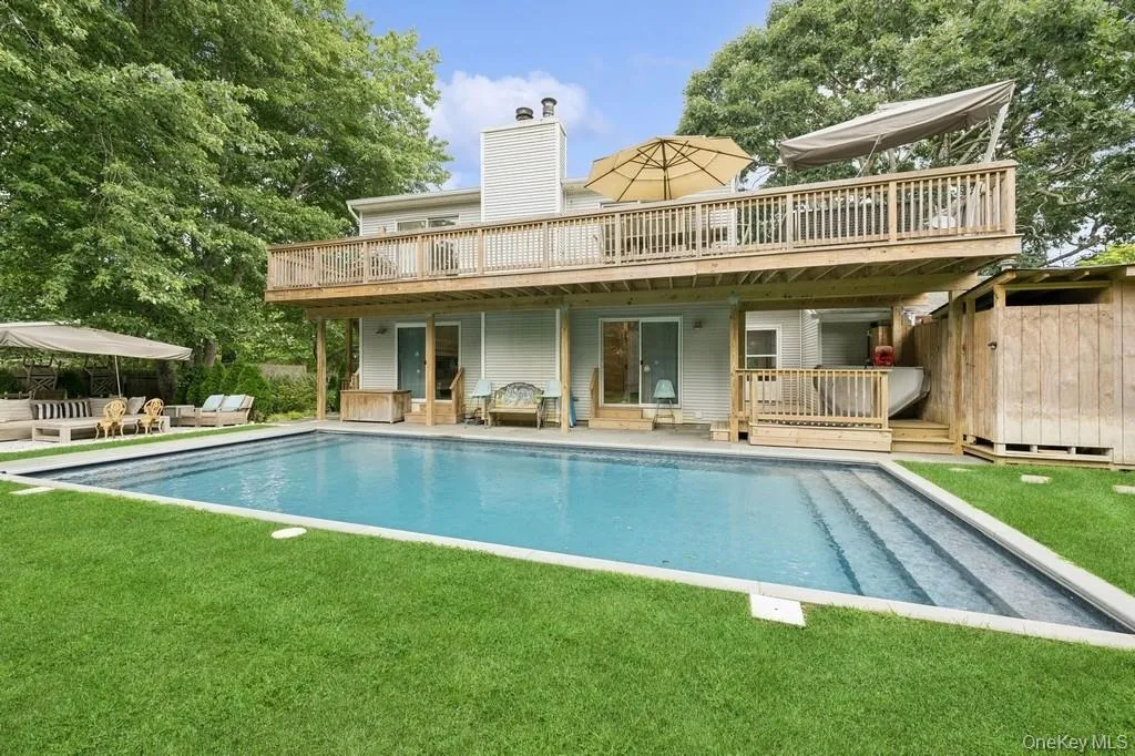 Rear view of property with a patio, a wooden deck, an outdoor pool, and a chimney Rear view of property with a patio, a wooden deck, an outdoor pool, and a chimney