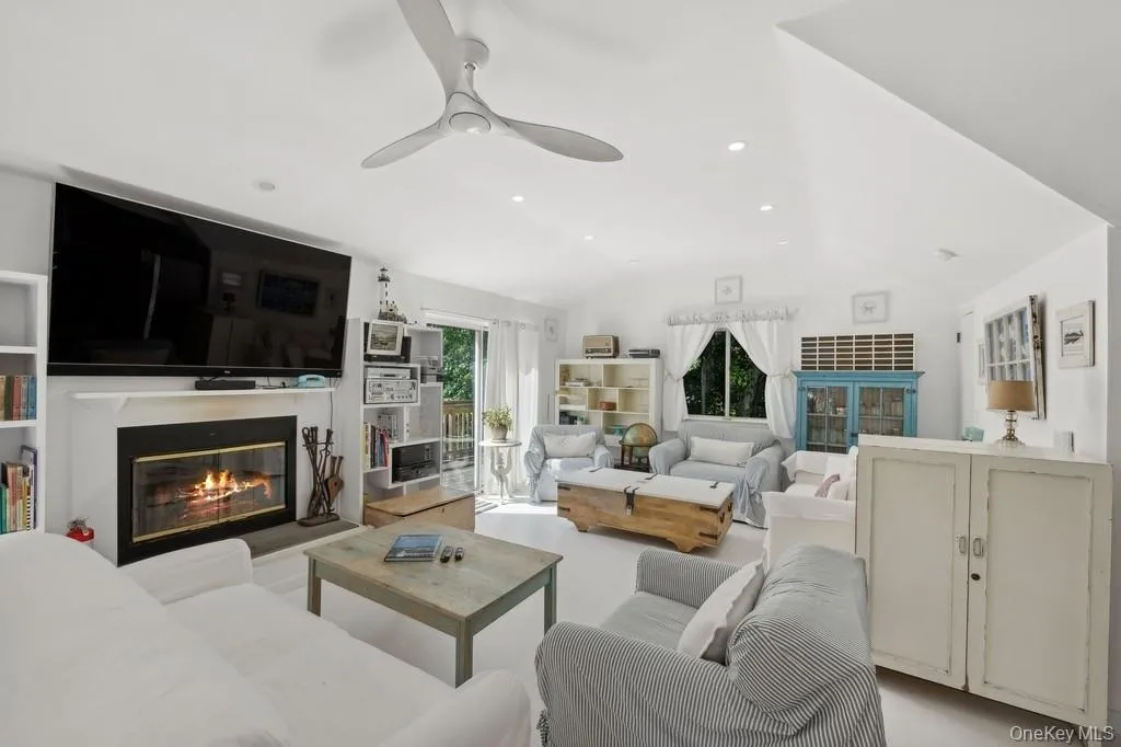 Living area featuring a glass covered fireplace, lofted ceiling, recessed lighting, and ceiling fan Living area featuring a glass covered fireplace, lofted ceiling, recessed lighting, and ceiling fan