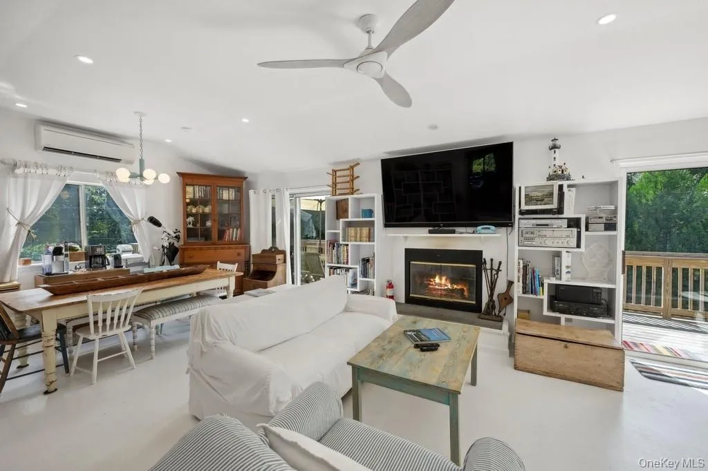 Living room featuring recessed lighting, a glass covered fireplace, an AC wall unit, a chandelier, and ceiling fan Living room featuring recessed lighting, a glass covered fireplace, an AC wall unit, a chandelier, and ceiling fan