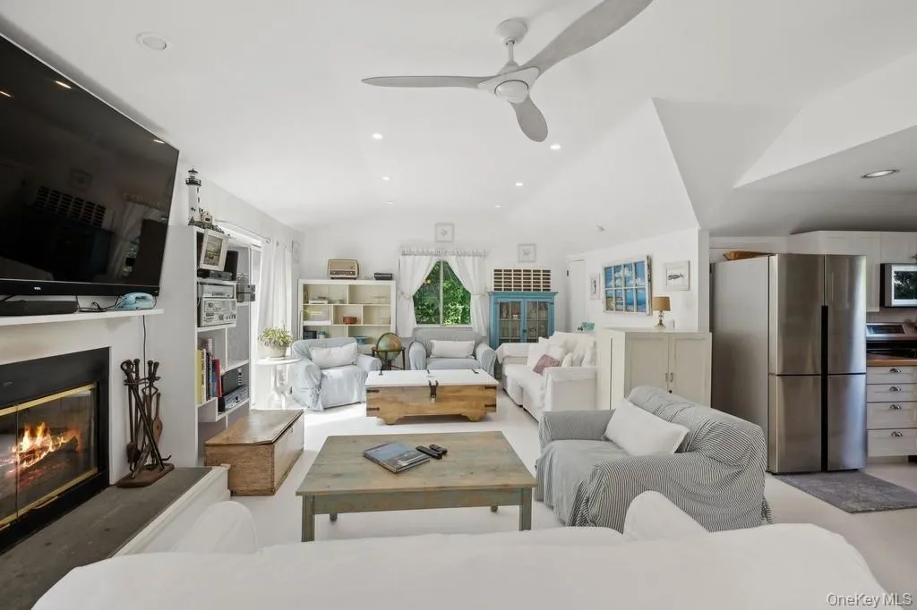 Living area featuring vaulted ceiling, recessed lighting, a glass covered fireplace, and ceiling fan Living area featuring vaulted ceiling, recessed lighting, a glass covered fireplace, and ceiling fan