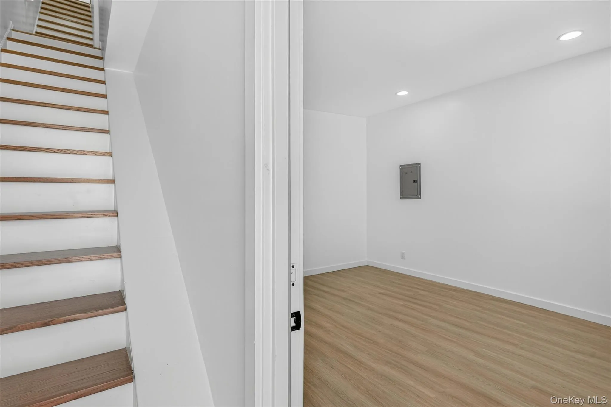 Staircase with wood finished floors, recessed lighting, and electric panel Staircase with wood finished floors, recessed lighting, and electric panel