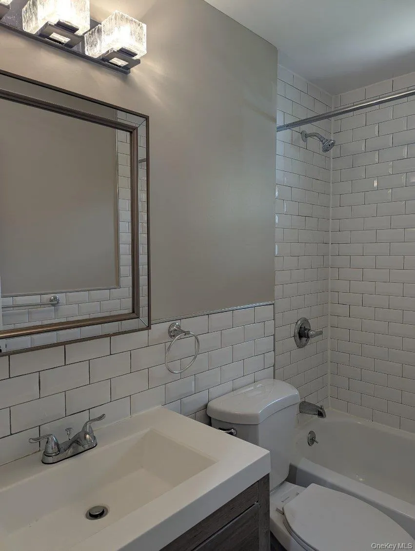 Full bath featuring bathing tub / shower combination, vanity, tile walls, and backsplash Full bath featuring bathing tub / shower combination, vanity, tile walls, and backsplash