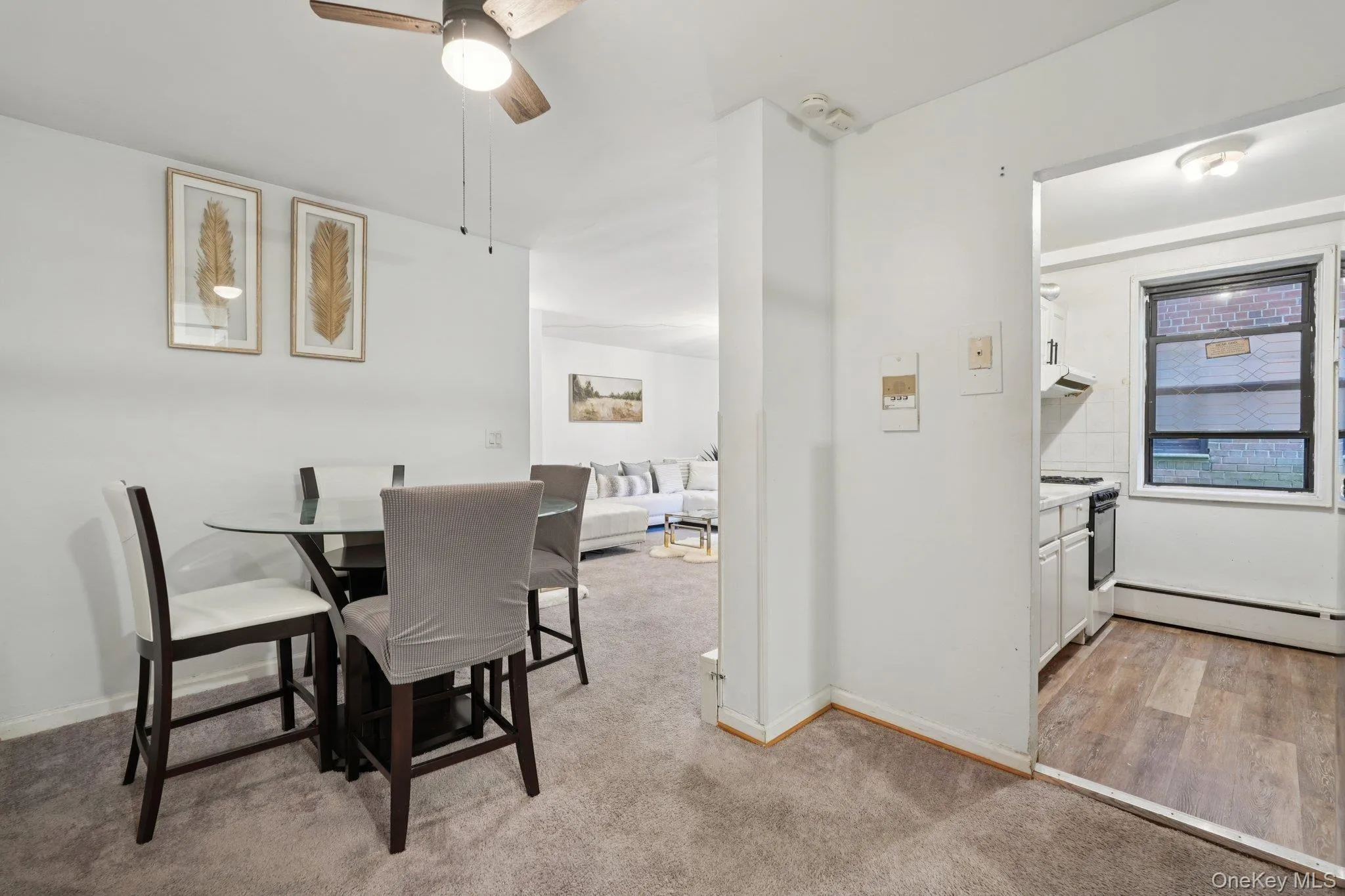 Dining room with baseboard heating, light colored carpet, and a ceiling fan Dining room with baseboard heating, light colored carpet, and a ceiling fan