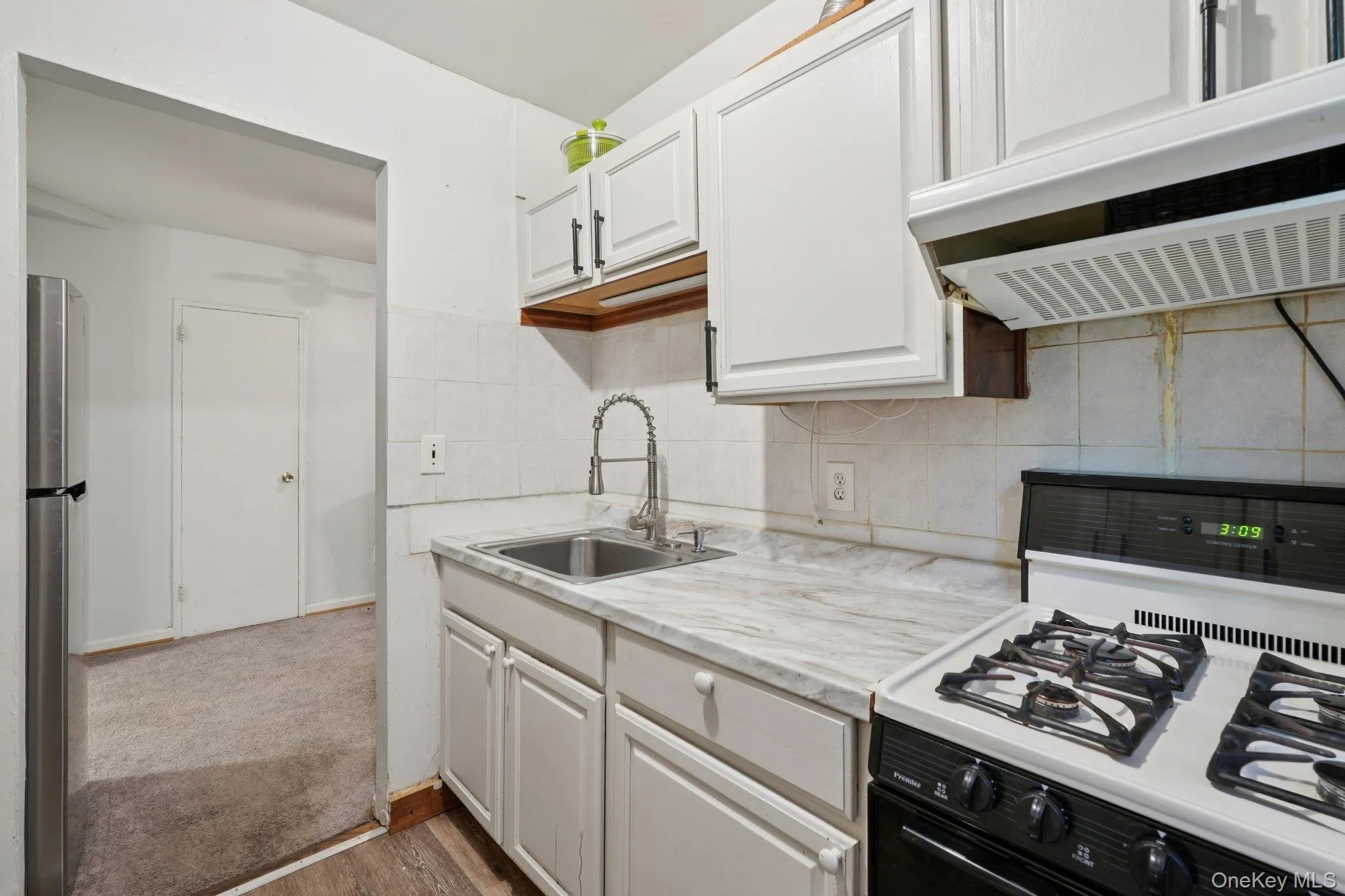 Kitchen featuring white gas range, light countertops, range hood, white cabinetry, and dark wood finished floors Kitchen featuring white gas range, light countertops, range hood, white cabinetry, and dark wood finished floors