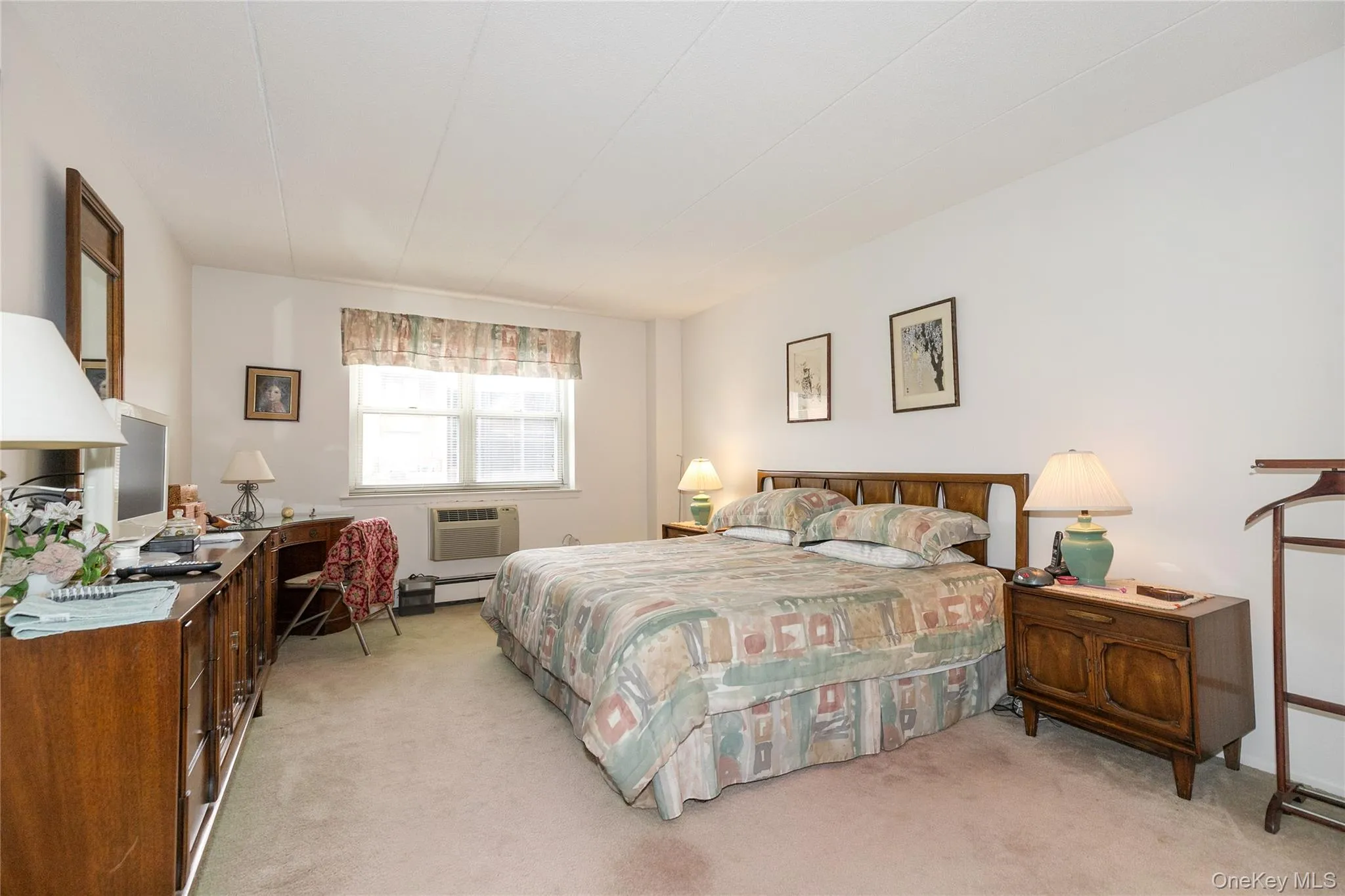 Bedroom featuring light colored carpet, an office area, and a baseboard radiator Bedroom featuring light colored carpet, an office area, and a baseboard radiator