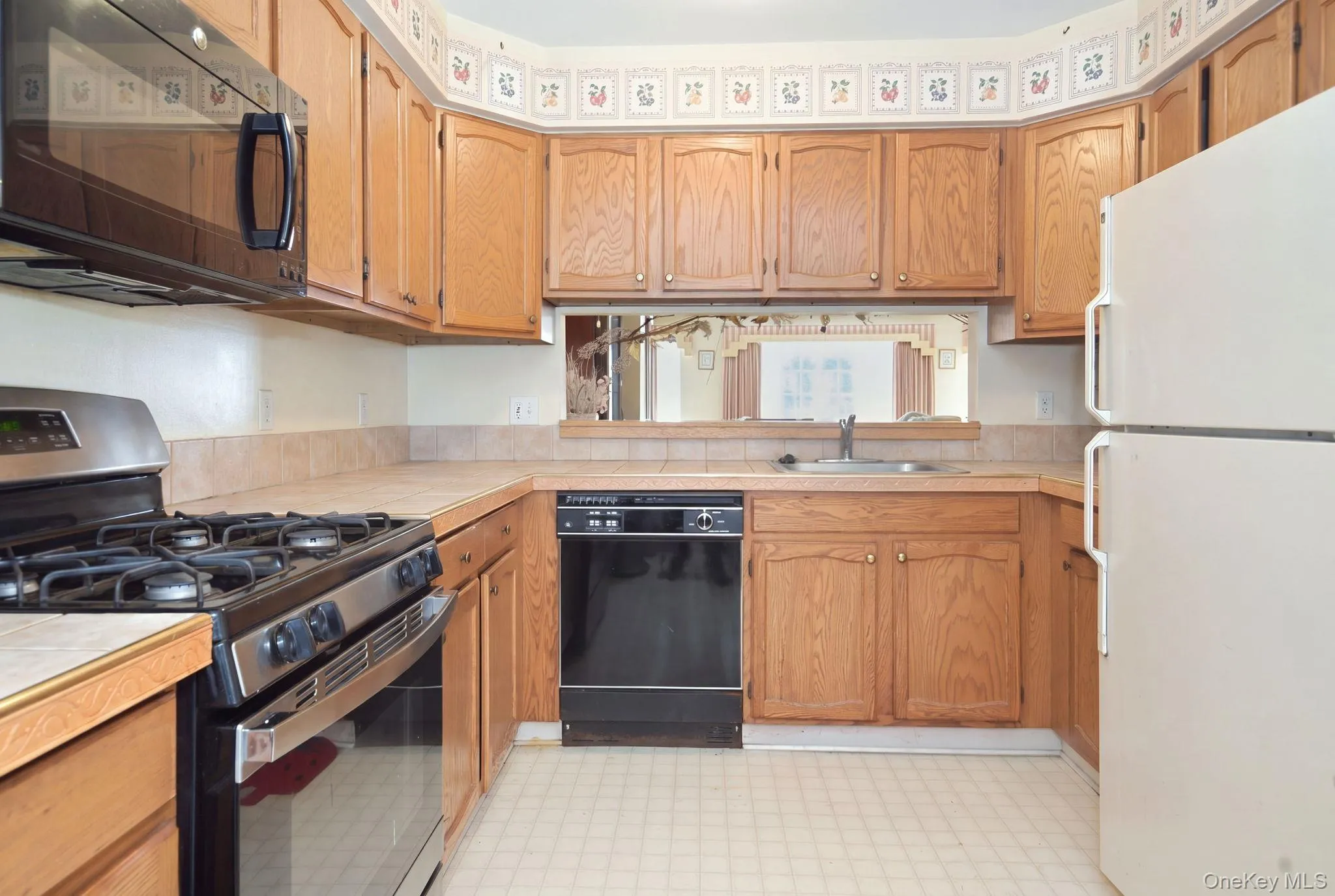 (Digitally decluttered) The kitchen's U-shaped layout, gas range and pass-through to the living room come into clear view. (Digitally decluttered) The kitchen's U-shaped layout, gas range and pass-through to the living room come into clear view.
