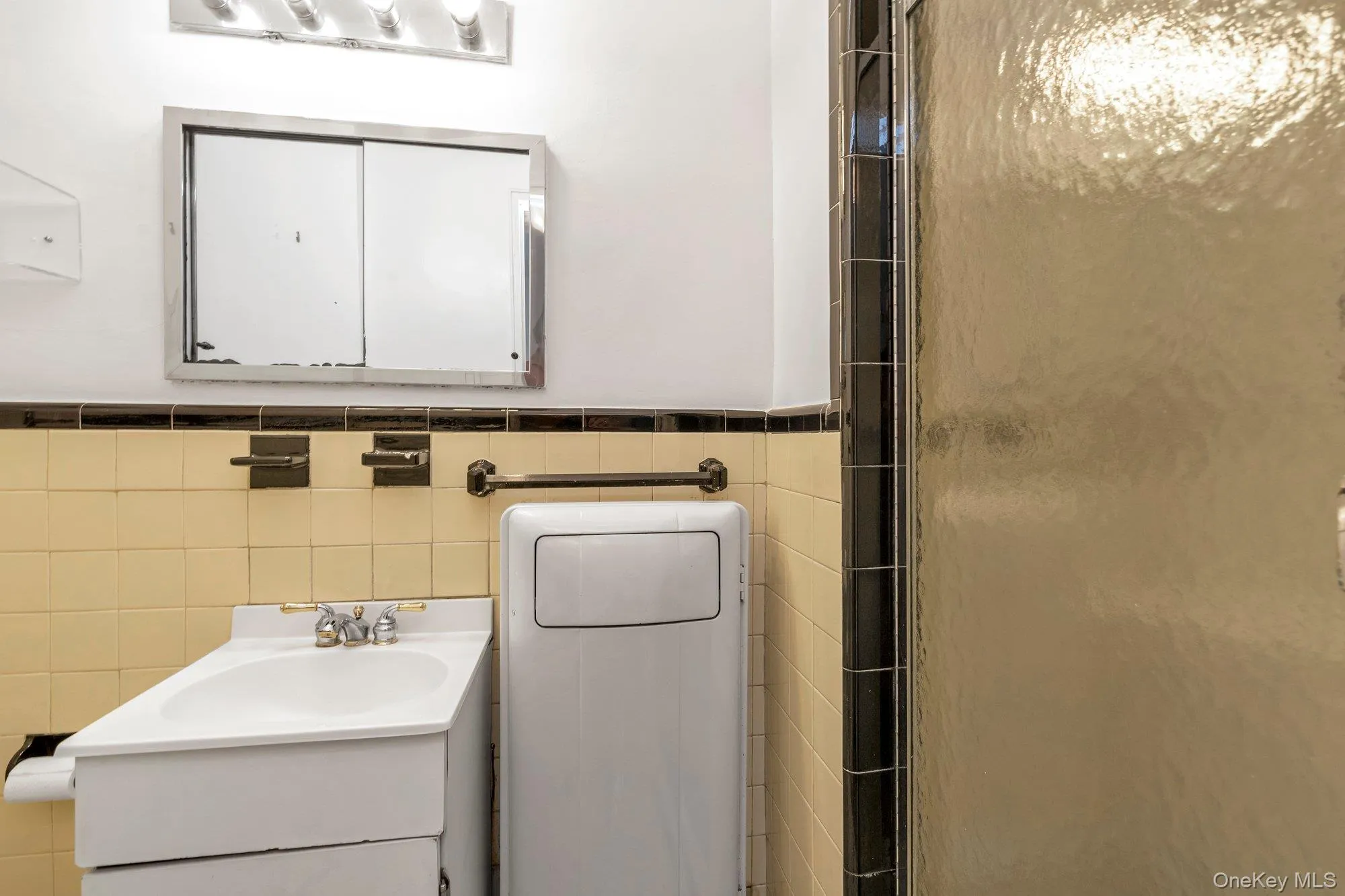 Bathroom with vanity, tile walls, an enclosed shower, and wainscoting Bathroom with vanity, tile walls, an enclosed shower, and wainscoting