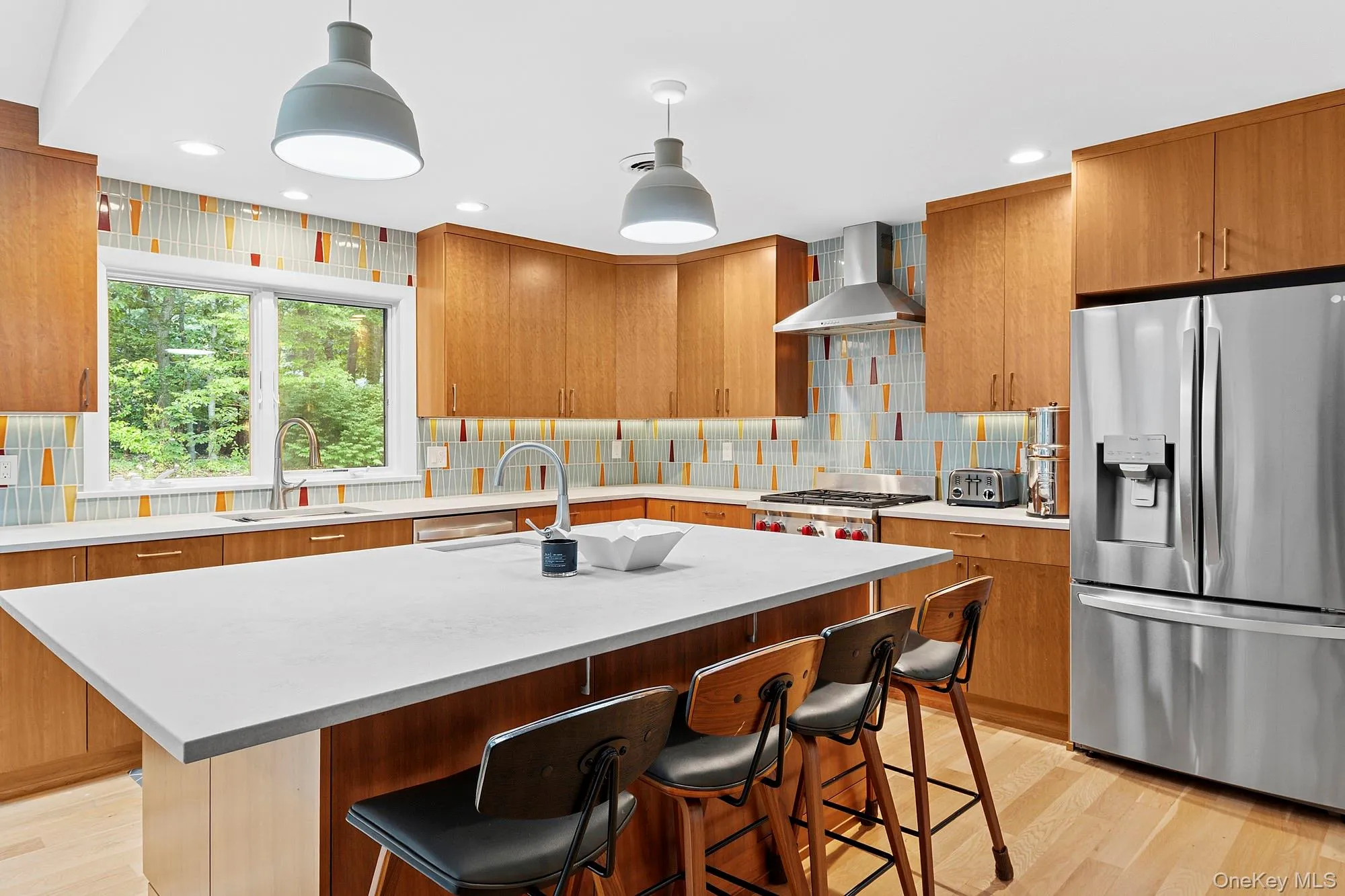 Kitchen featuring stainless steel fridge, a kitchen breakfast bar, light wood finished floors, hanging light fixtures, and recessed lighting Kitchen featuring stainless steel fridge, a kitchen breakfast bar, light wood finished floors, hanging light fixtures, and recessed lighting