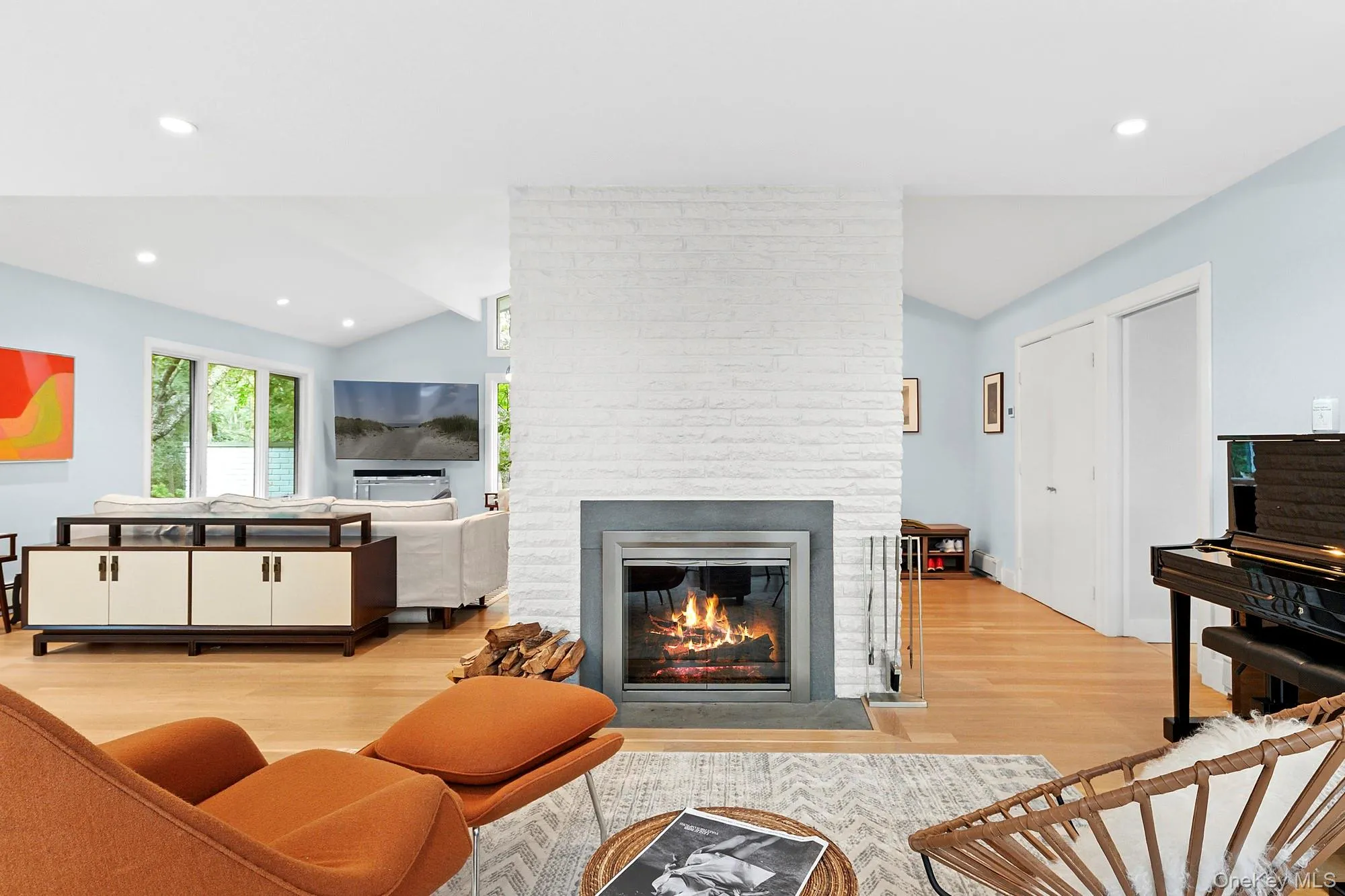 Living area featuring lofted ceiling, recessed lighting, light wood finished floors, and a brick fireplace Living area featuring lofted ceiling, recessed lighting, light wood finished floors, and a brick fireplace
