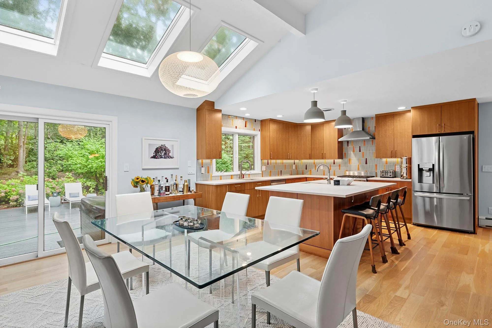 Dining space featuring light wood-style flooring, a skylight, beam ceiling, and high vaulted ceiling Dining space featuring light wood-style flooring, a skylight, beam ceiling, and high vaulted ceiling