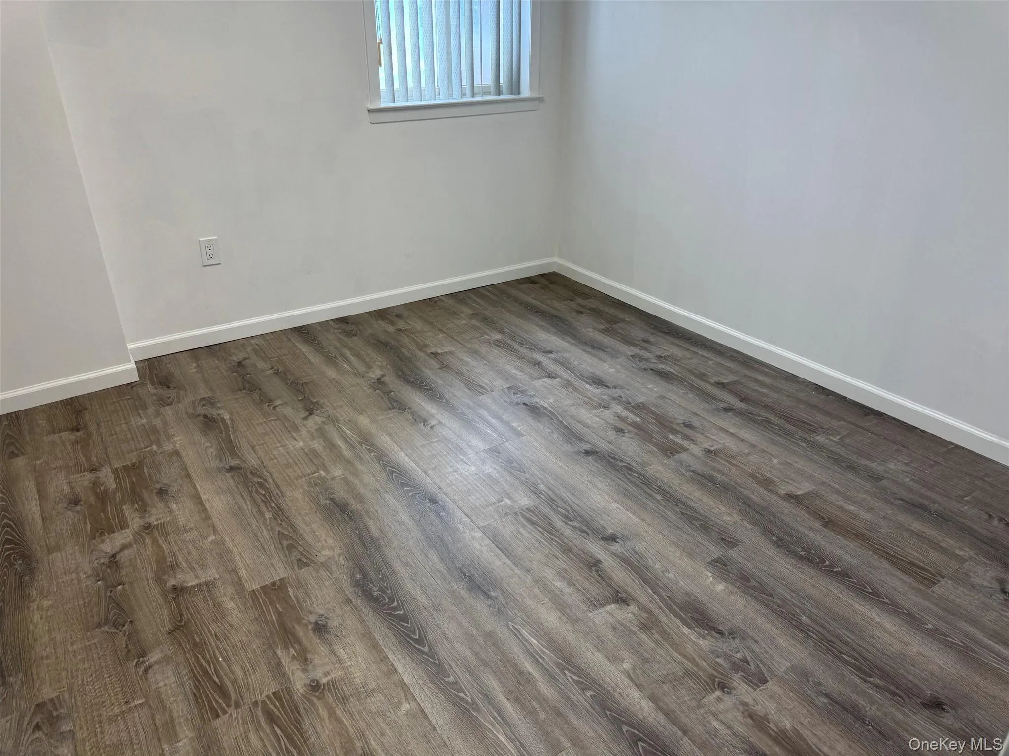 Unfurnished room with dark wood-style flooring and baseboards Unfurnished room with dark wood-style flooring and baseboards