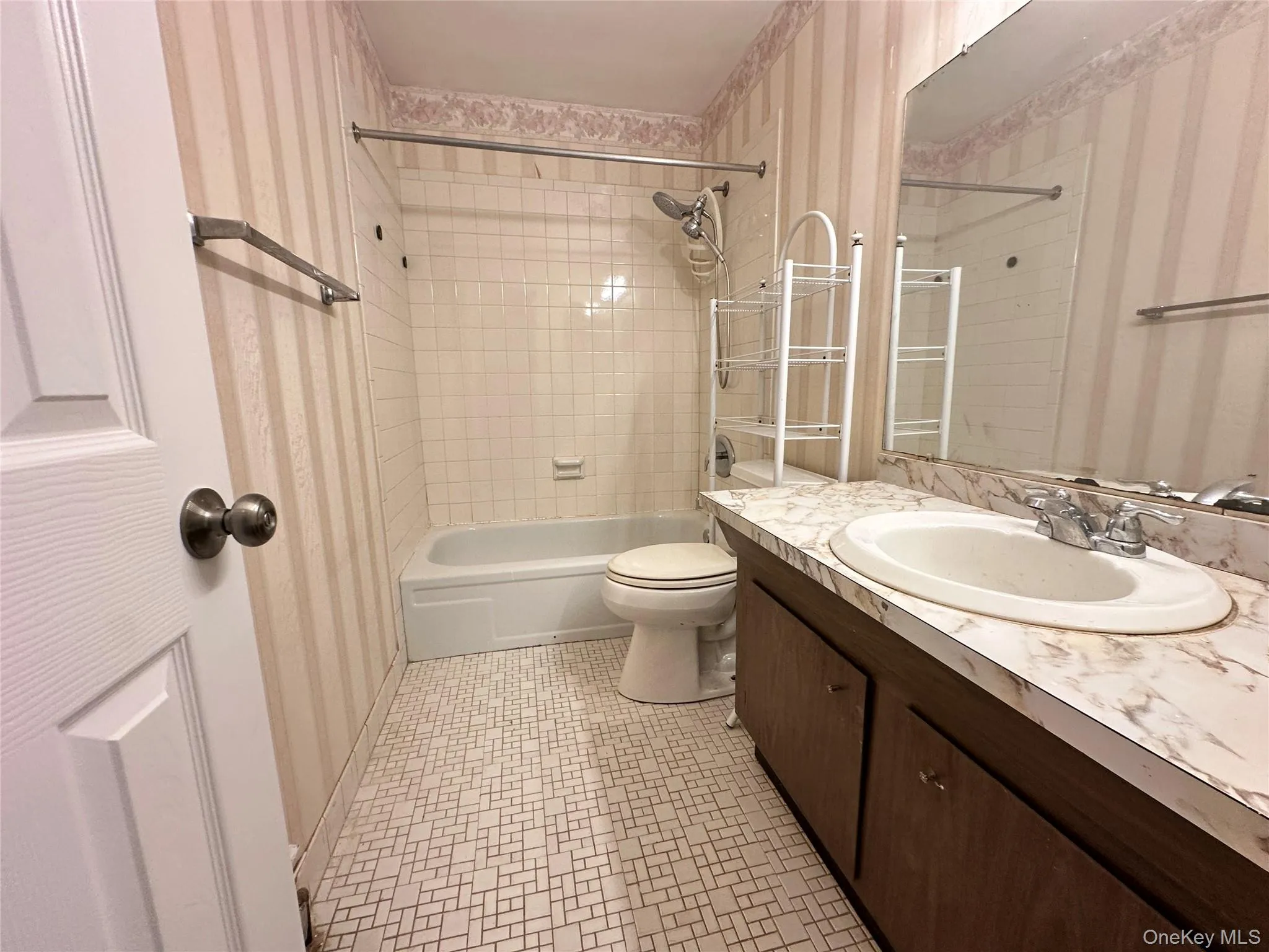 Full bath featuring wallpapered walls, vanity, and washtub / shower combination Full bath featuring wallpapered walls, vanity, and washtub / shower combination