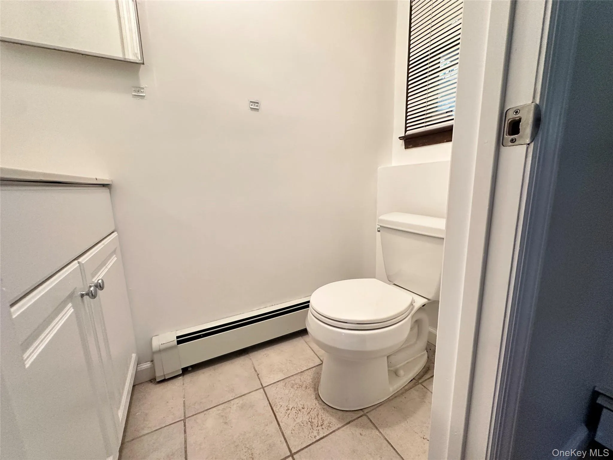 Bathroom featuring baseboard heating, vanity, and light tile patterned flooring Bathroom featuring baseboard heating, vanity, and light tile patterned flooring