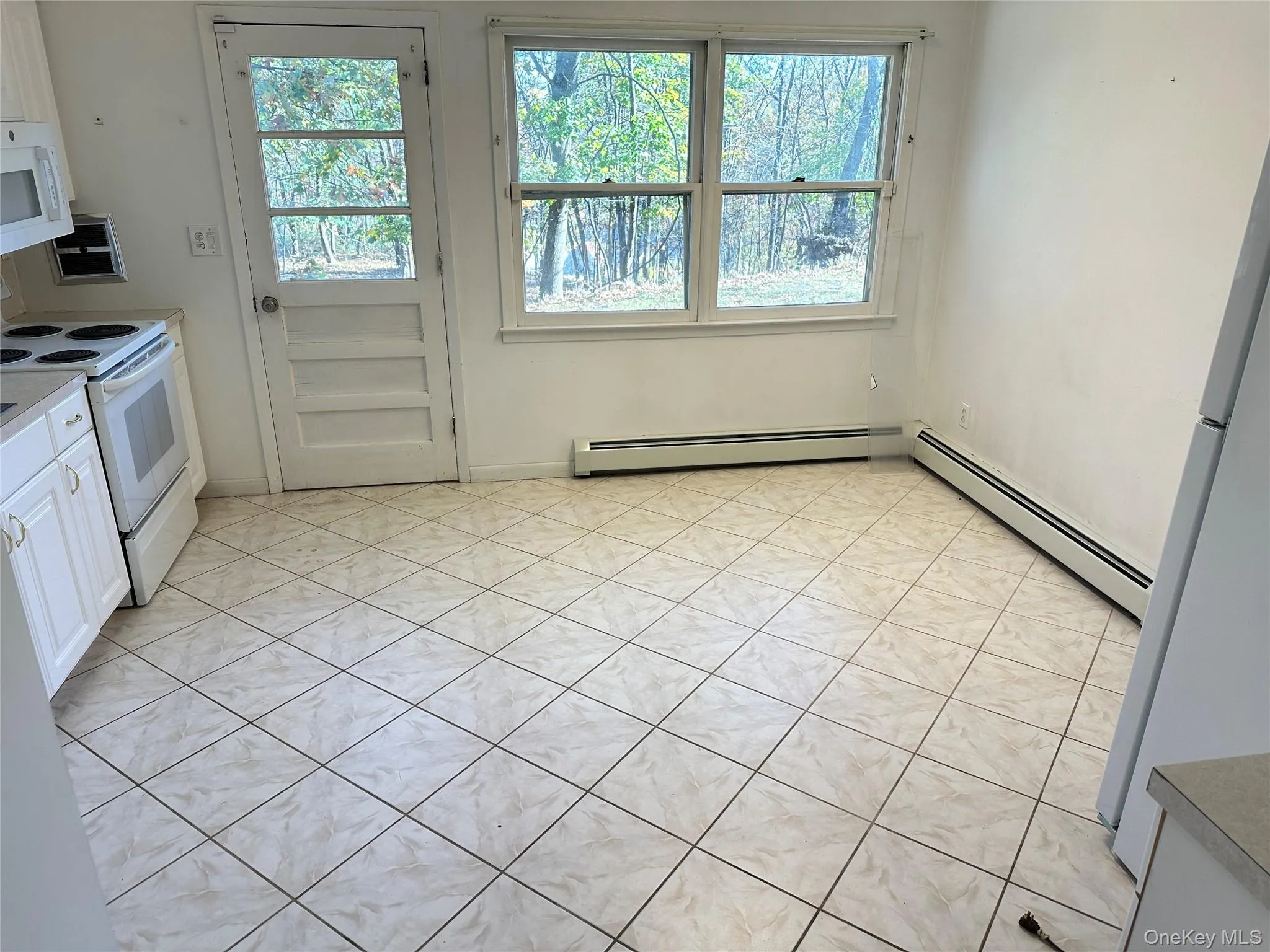 Kitchen with white appliances, light tile patterned floors, light countertops, white cabinets, and baseboard heating Kitchen with white appliances, light tile patterned floors, light countertops, white cabinets, and baseboard heating