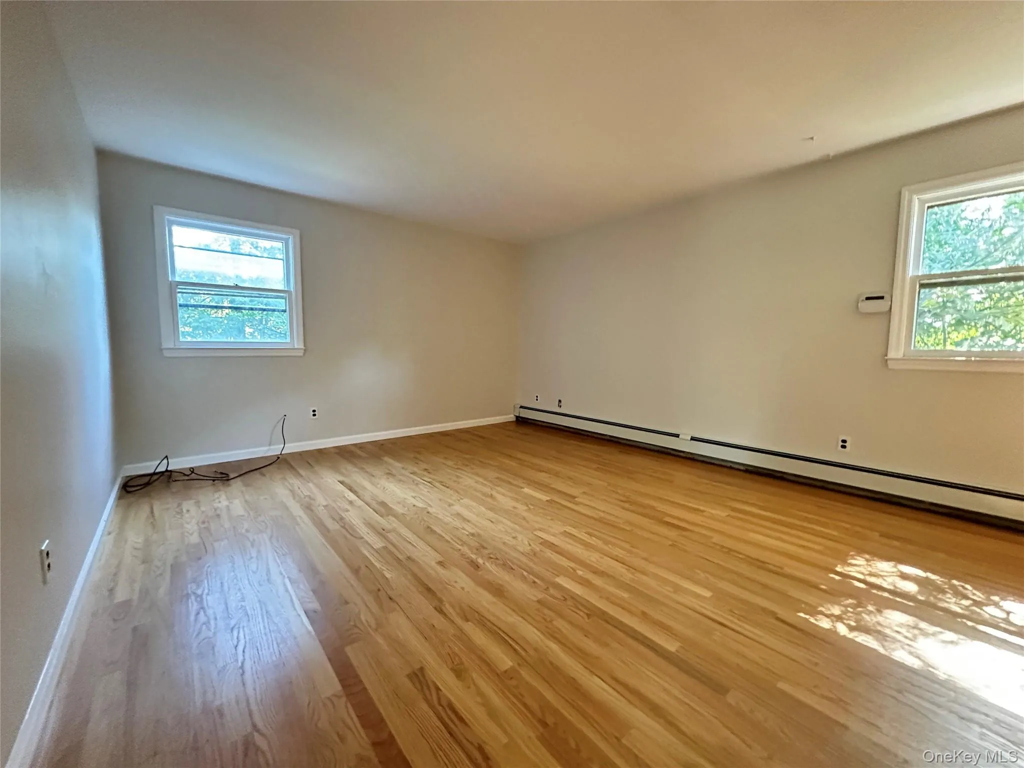 Spare room with light wood-type flooring and baseboard heating Spare room with light wood-type flooring and baseboard heating