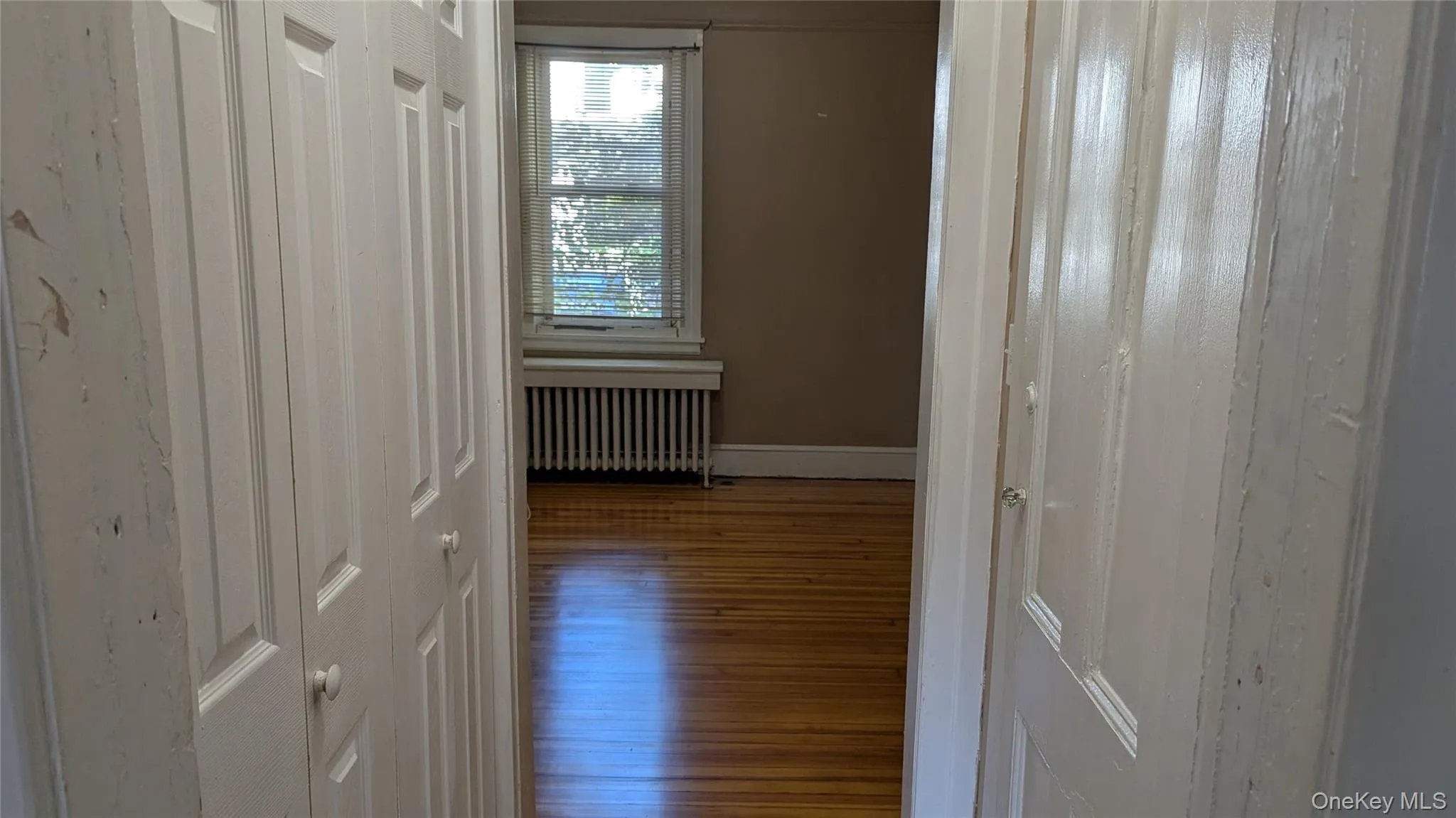 Corridor featuring radiator heating unit and wood finished floors Corridor featuring radiator heating unit and wood finished floors