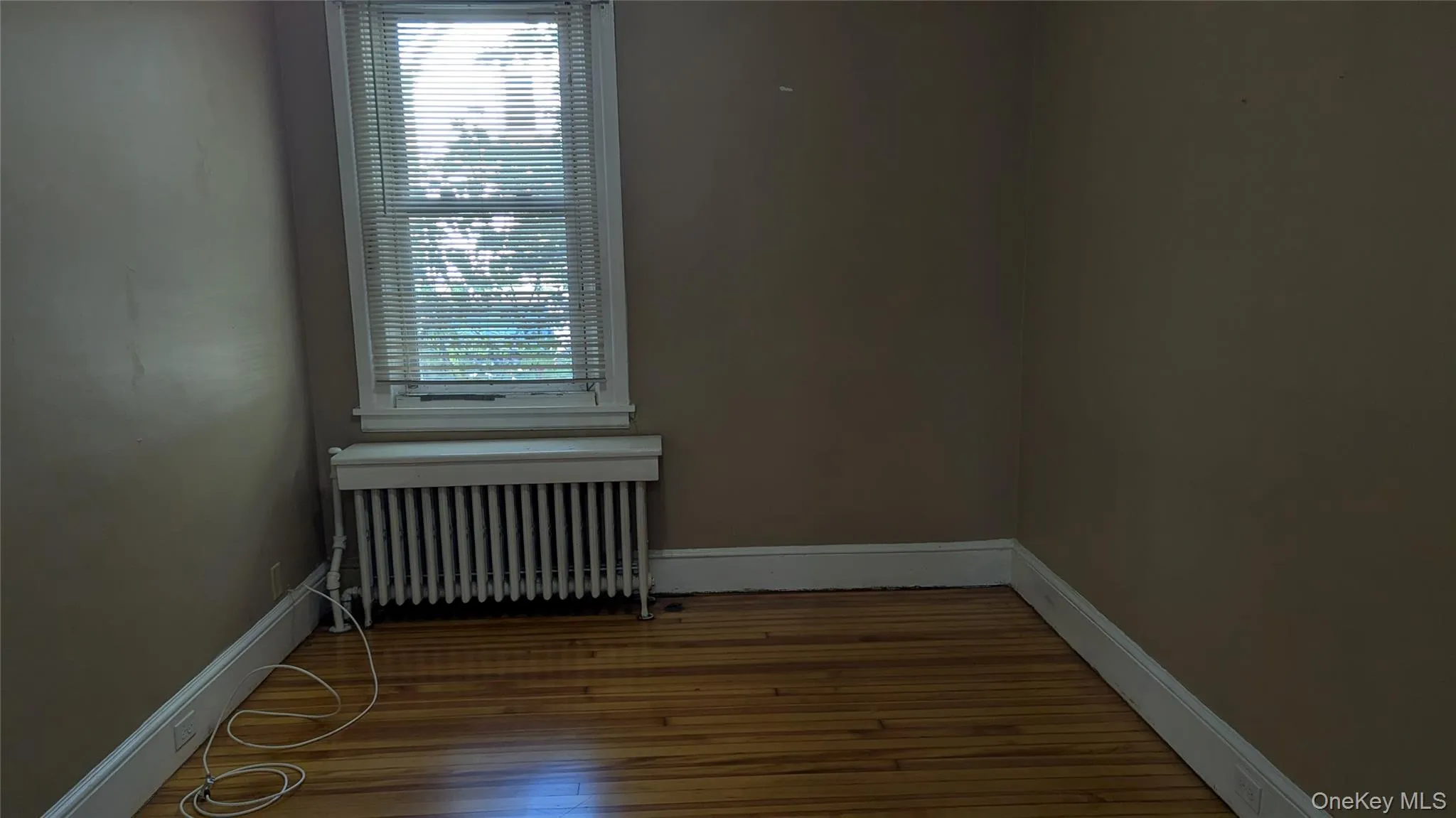 Spare room featuring radiator heating unit and light wood-style floors Spare room featuring radiator heating unit and light wood-style floors