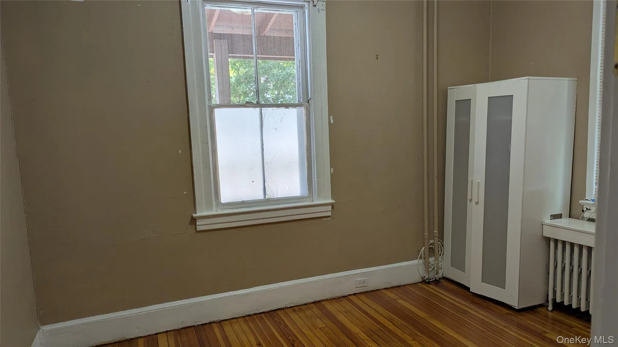 Unfurnished room featuring radiator and wood-type flooring Unfurnished room featuring radiator and wood-type flooring