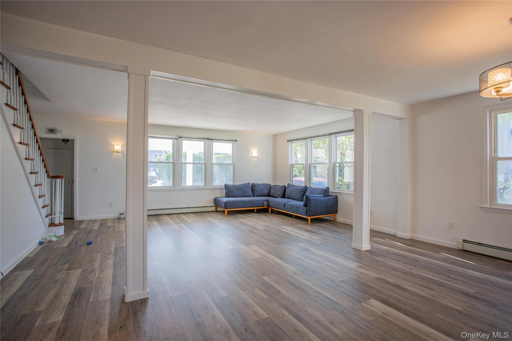 Living area featuring stairway, plenty of natural light, wood finished floors, and a baseboard heating unit Living area featuring stairway, plenty of natural light, wood finished floors, and a baseboard heating unit