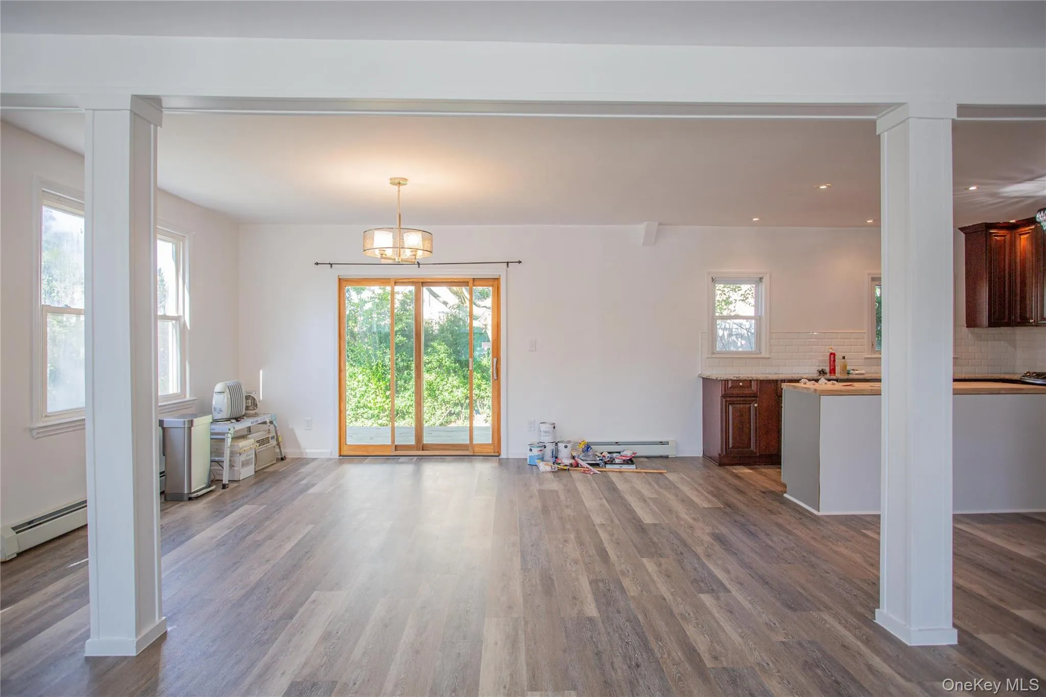 Unfurnished living room featuring decorative columns, dark wood-type flooring, baseboard heating, a chandelier, and recessed lighting Unfurnished living room featuring decorative columns, dark wood-type flooring, baseboard heating, a chandelier, and recessed lighting