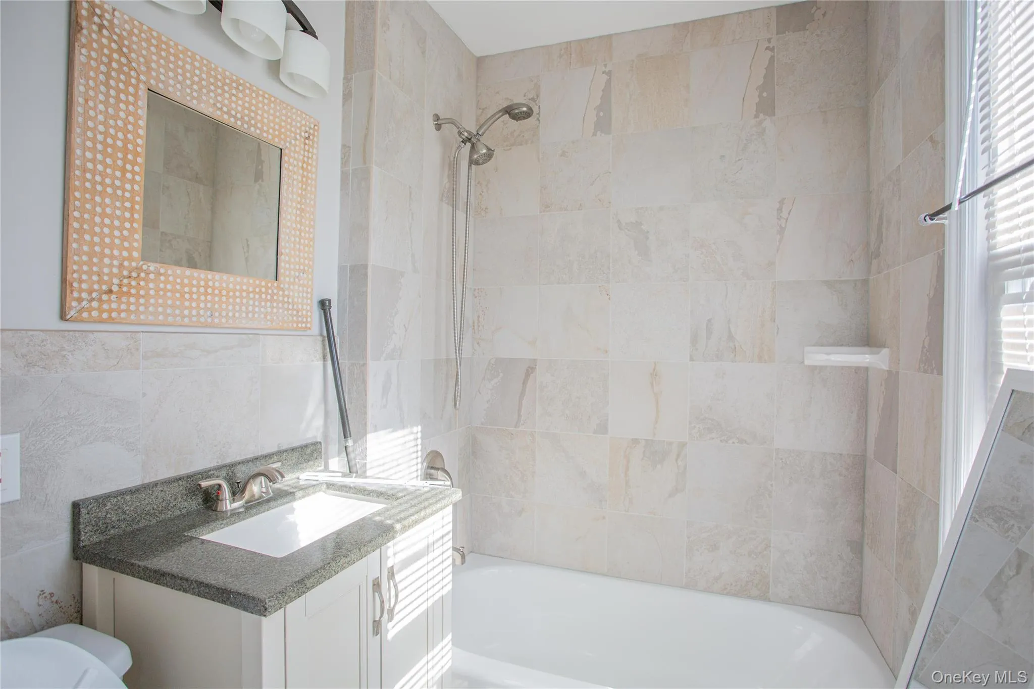 Bathroom with washtub / shower combination, tile walls, vanity, and healthy amount of natural light Bathroom with washtub / shower combination, tile walls, vanity, and healthy amount of natural light