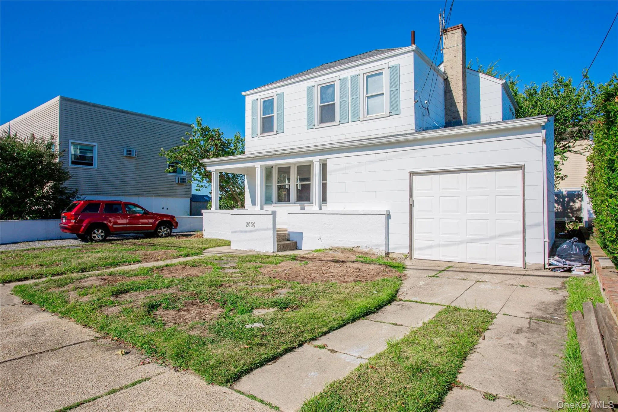 Traditional-style house with driveway, a porch, a chimney, and a garage Traditional-style house with driveway, a porch, a chimney, and a garage