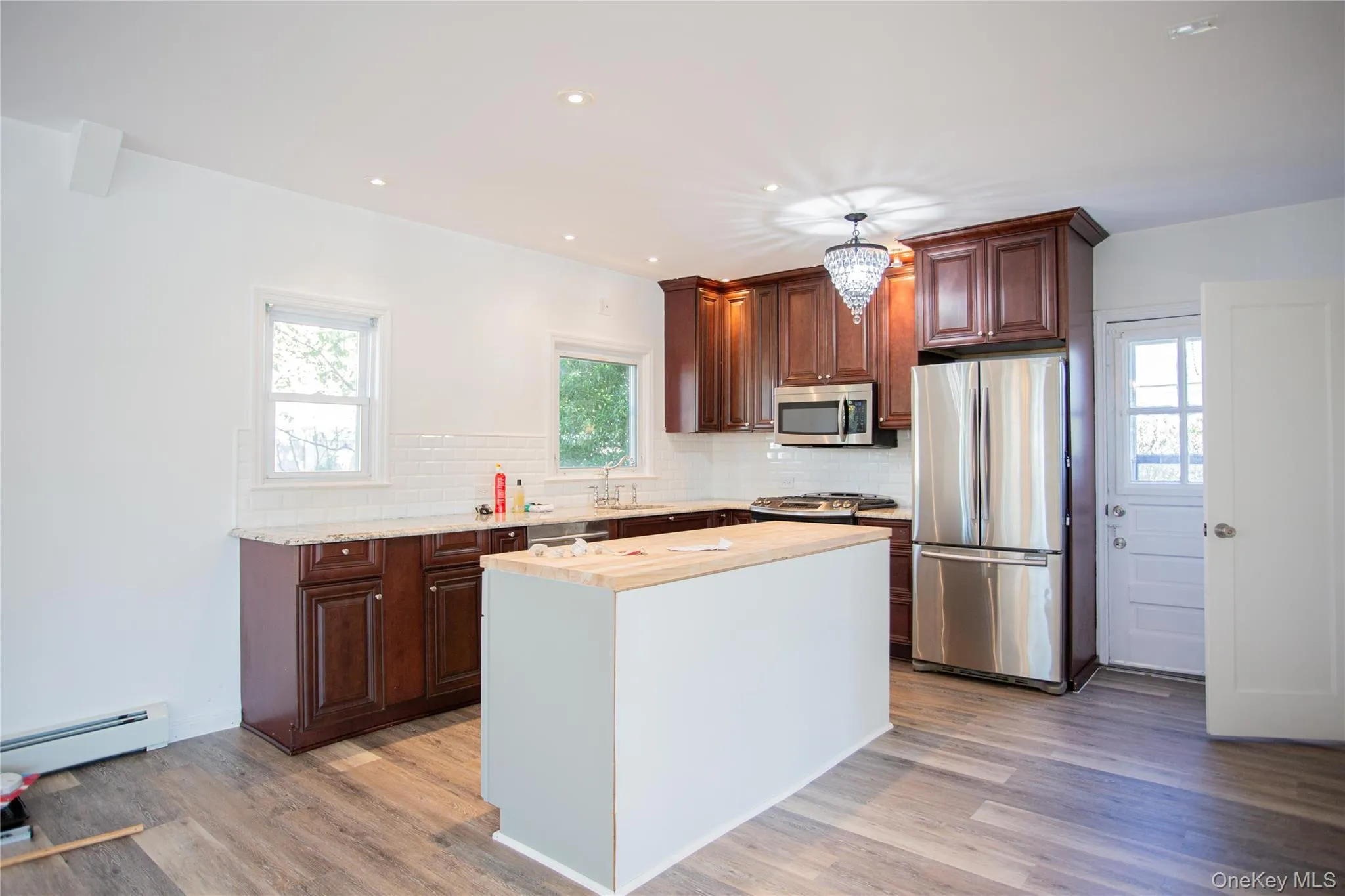 Kitchen featuring appliances with stainless steel finishes, recessed lighting, a center island, tasteful backsplash, and light wood finished floors Kitchen featuring appliances with stainless steel finishes, recessed lighting, a center island, tasteful backsplash, and light wood finished floors