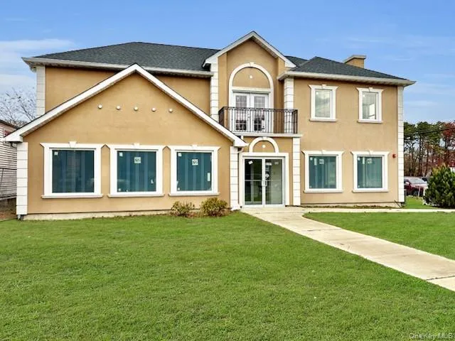 Back of property with a balcony, stucco siding, french doors, and a yard Back of property with a balcony, stucco siding, french doors, and a yard