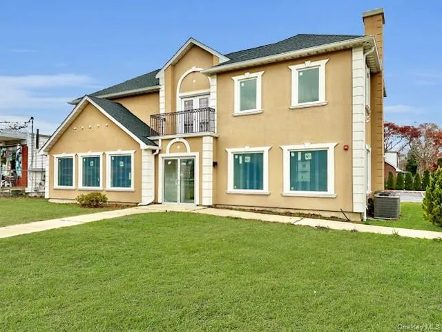 View of front facade featuring a balcony, stucco siding, a chimney, and a front lawn View of front facade featuring a balcony, stucco siding, a chimney, and a front lawn