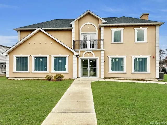 View of front of house with stucco siding, a balcony, french doors, a chimney, and a front lawn View of front of house with stucco siding, a balcony, french doors, a chimney, and a front lawn