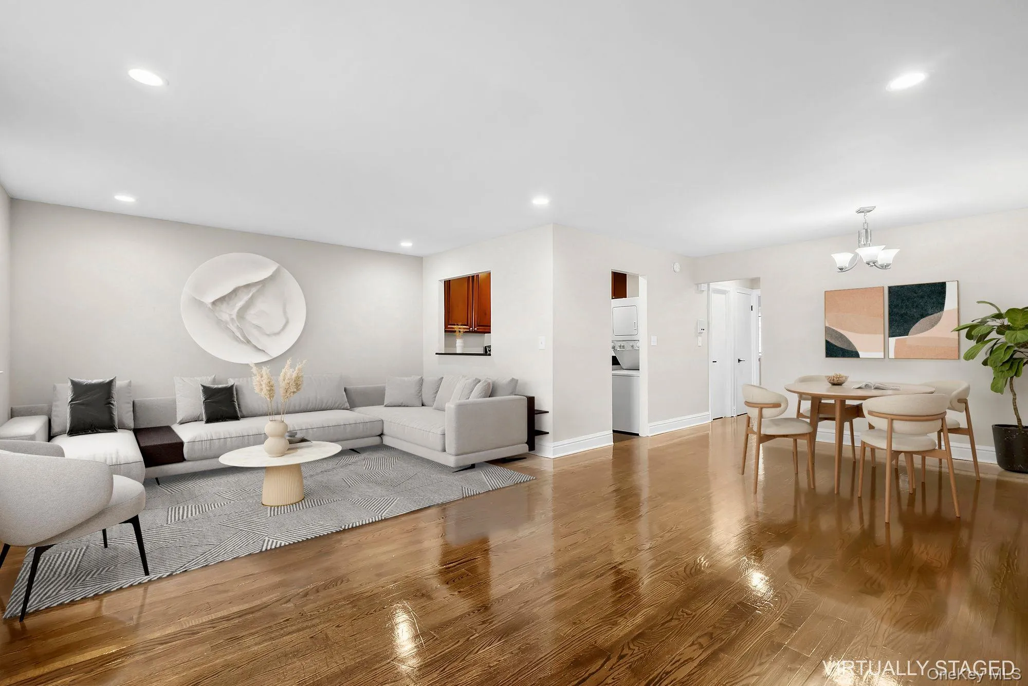 Living area featuring recessed lighting, light wood-style floors, a chandelier, and estacked washer and dryer Living area featuring recessed lighting, light wood-style floors, a chandelier, and estacked washer and dryer