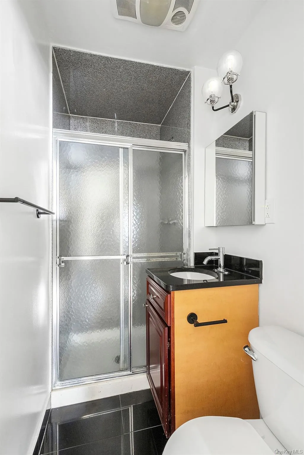 Full bathroom with vanity, a stall shower, and dark tile patterned flooring Full bathroom with vanity, a stall shower, and dark tile patterned flooring